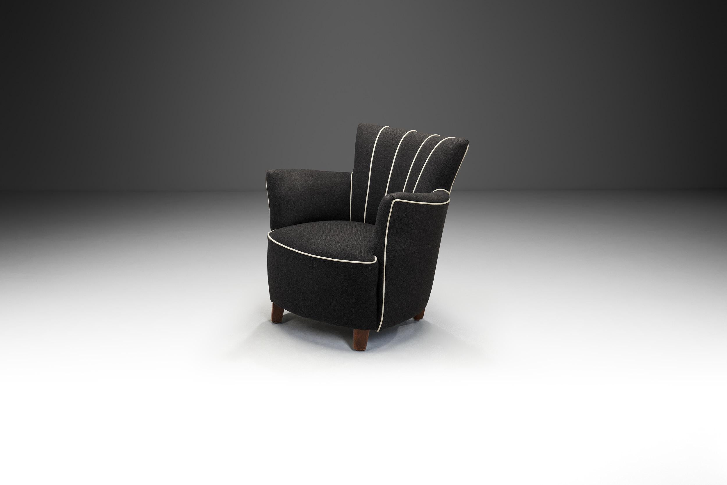This 20th-century European armchair is a striking example of streamlined design, reflecting the era’s embrace of clean lines, functional form, and understated elegance.

The chair is fully upholstered in a deep black fabric, with white lining along