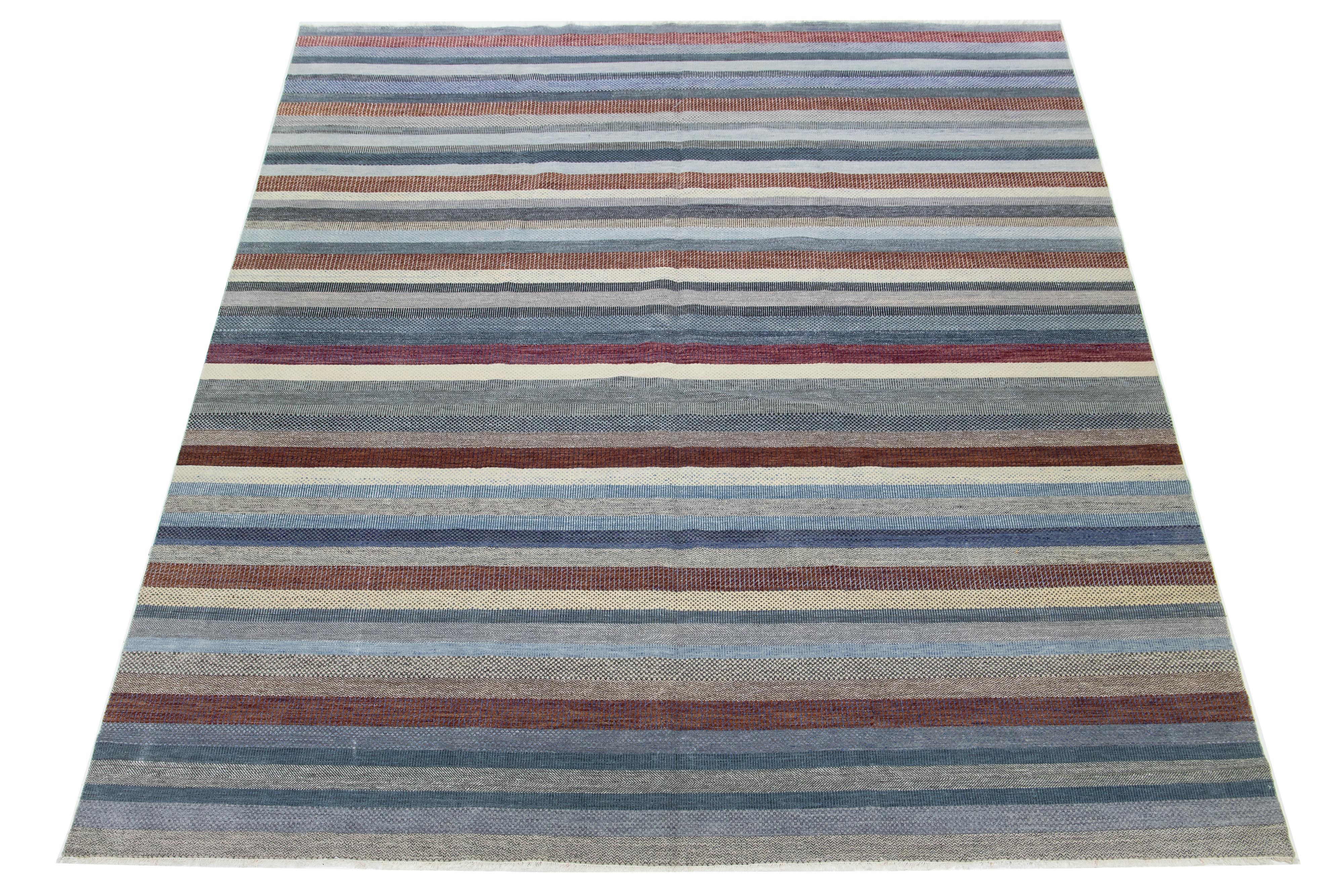 This beautifully hand-knotted wool rug features a modern design. It showcases a carefully crafted field in shades of gray, blue, and rust, adorned with intricate geometric patterns.

This rug measures 11'10
