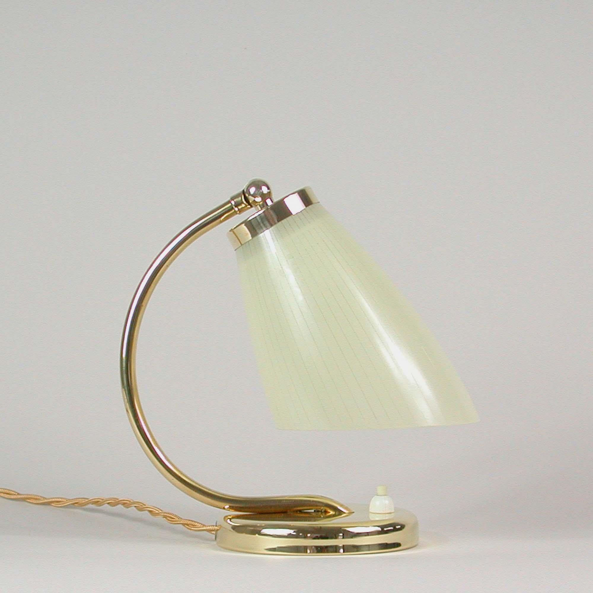 This pretty table lamp or bedside lamp was designed and manufactured in Sweden in the 1950s. It features an opaline striped cream colored lamp shade with brass base. The light has been rewired with new fabric cord and re-electrified with new E27