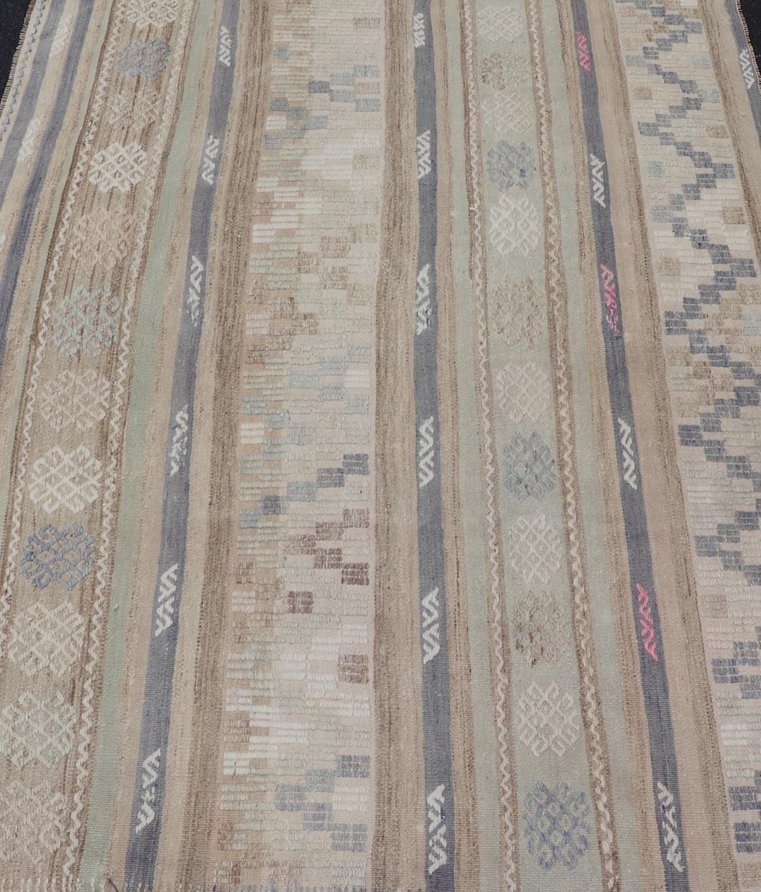 This flat-woven Kilim from Turkey features an enticing composition consisting of stripes with fascinating geometric designs rendered in natural tones of brown and gray, as well as some light green shades. 

Measures: 4'2 x 5'4 

Vintage Kilim with