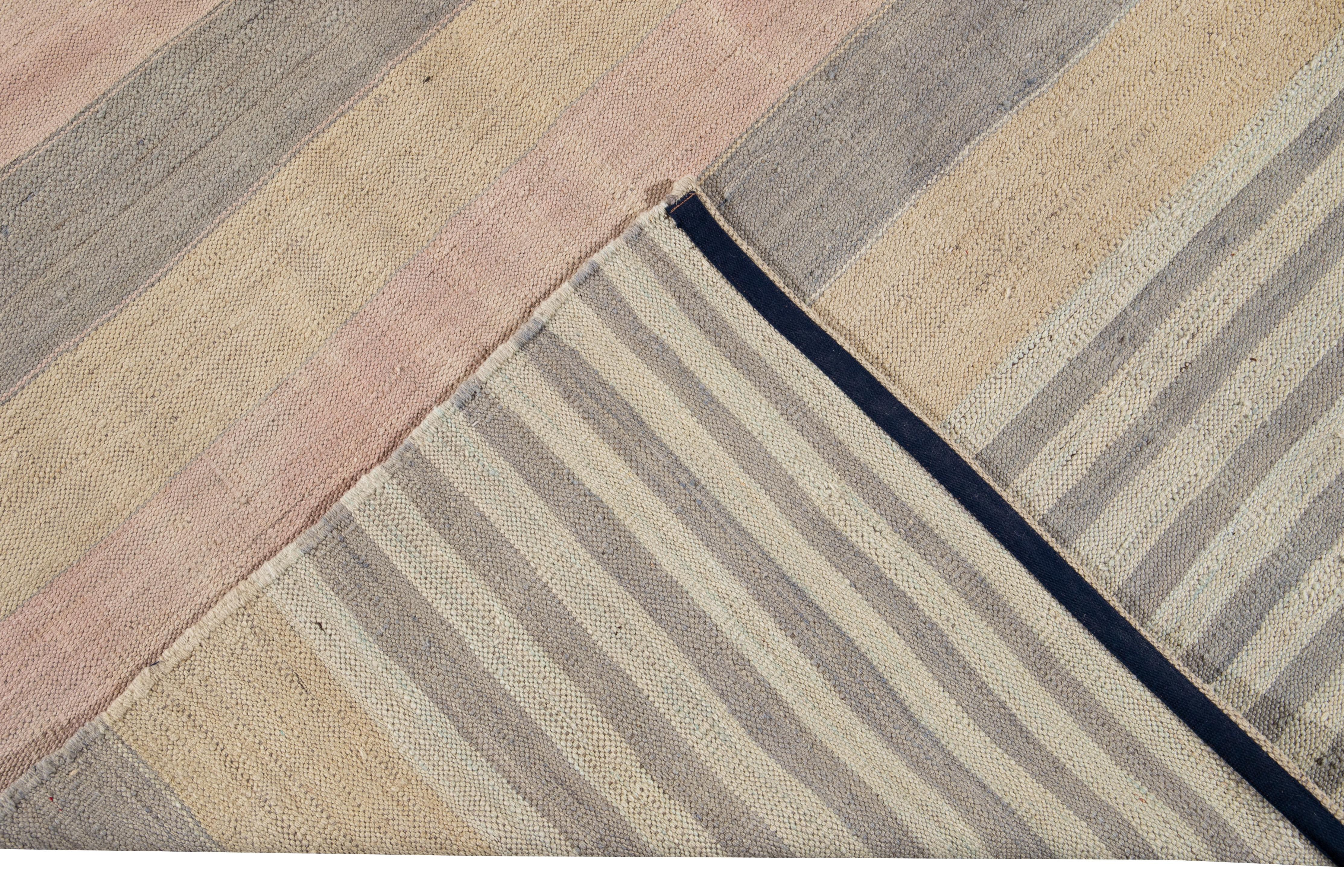 Beautiful modern flat-weave Kilim hand knotted wool rug. This rug has a field of peach, pink, and gray color in a gorgeous all-over geometric stripe design.

This rug measures 8'7