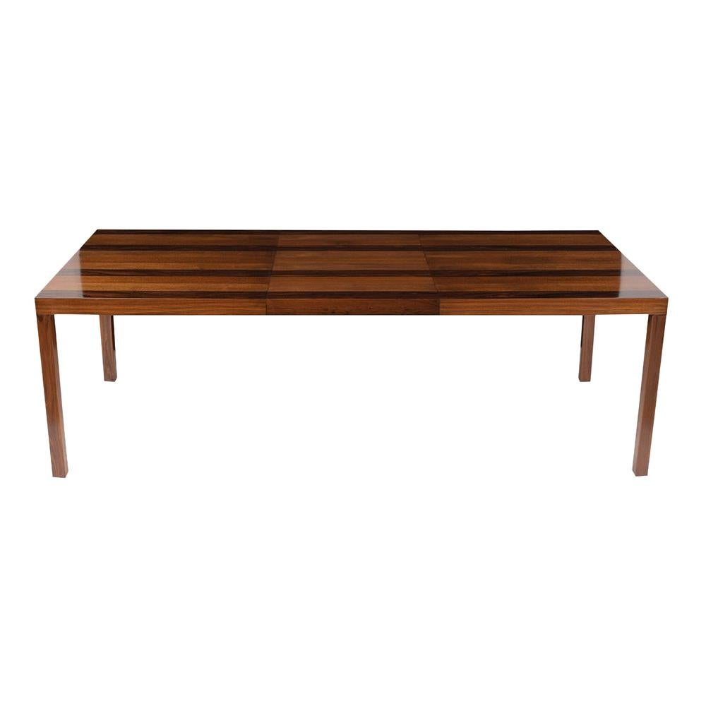 An extraordinary mid-century danish extendable dining table by Dyrlund has been completely restored and features a clean line three-striped design with a newly lacquered finish. The top has three parallel oak wood stripes divided by walnut veneers
