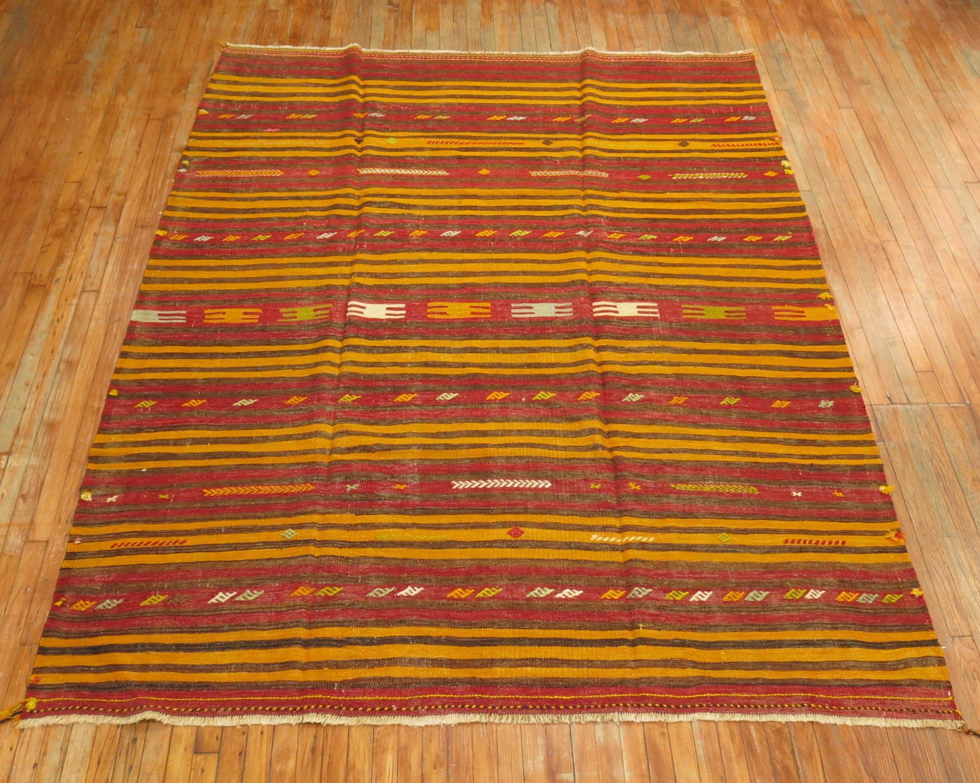 An intermediate size midcentury handwoven striped Turkish Kilim in red, orange, rust and brown accents. Has somewhat of a nomadic feel to it,

circa mid-20th century, measures: 7'4” x 9'8”.