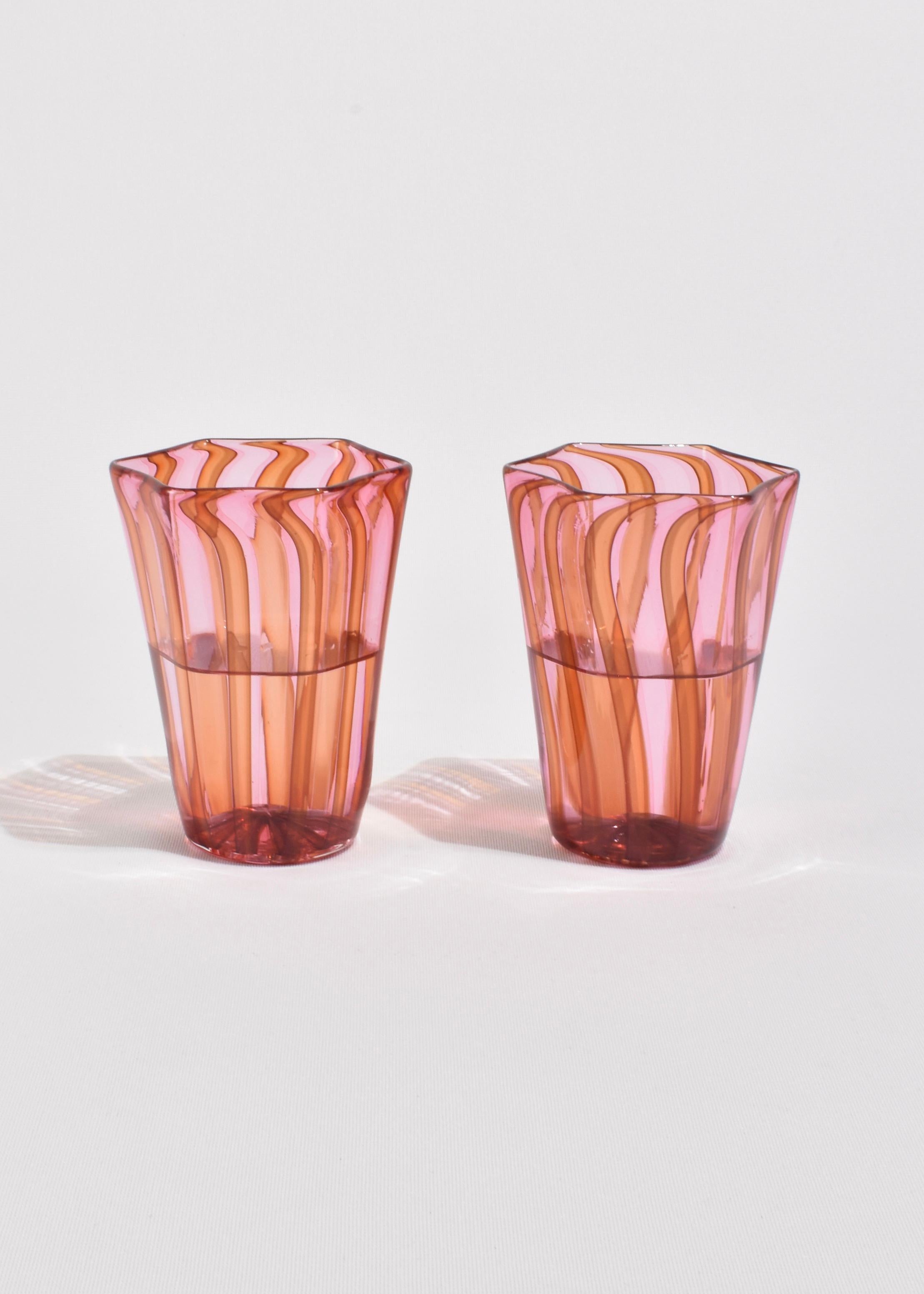 Nuestro juego de cristal de inspiración veneciana reúne vibrantes rayas rosas y naranjas con un característico borde hexagonal y una base redondeada. Estos vasos, que forman parte de nuestra nueva colección interna, combinan tonos modernos con