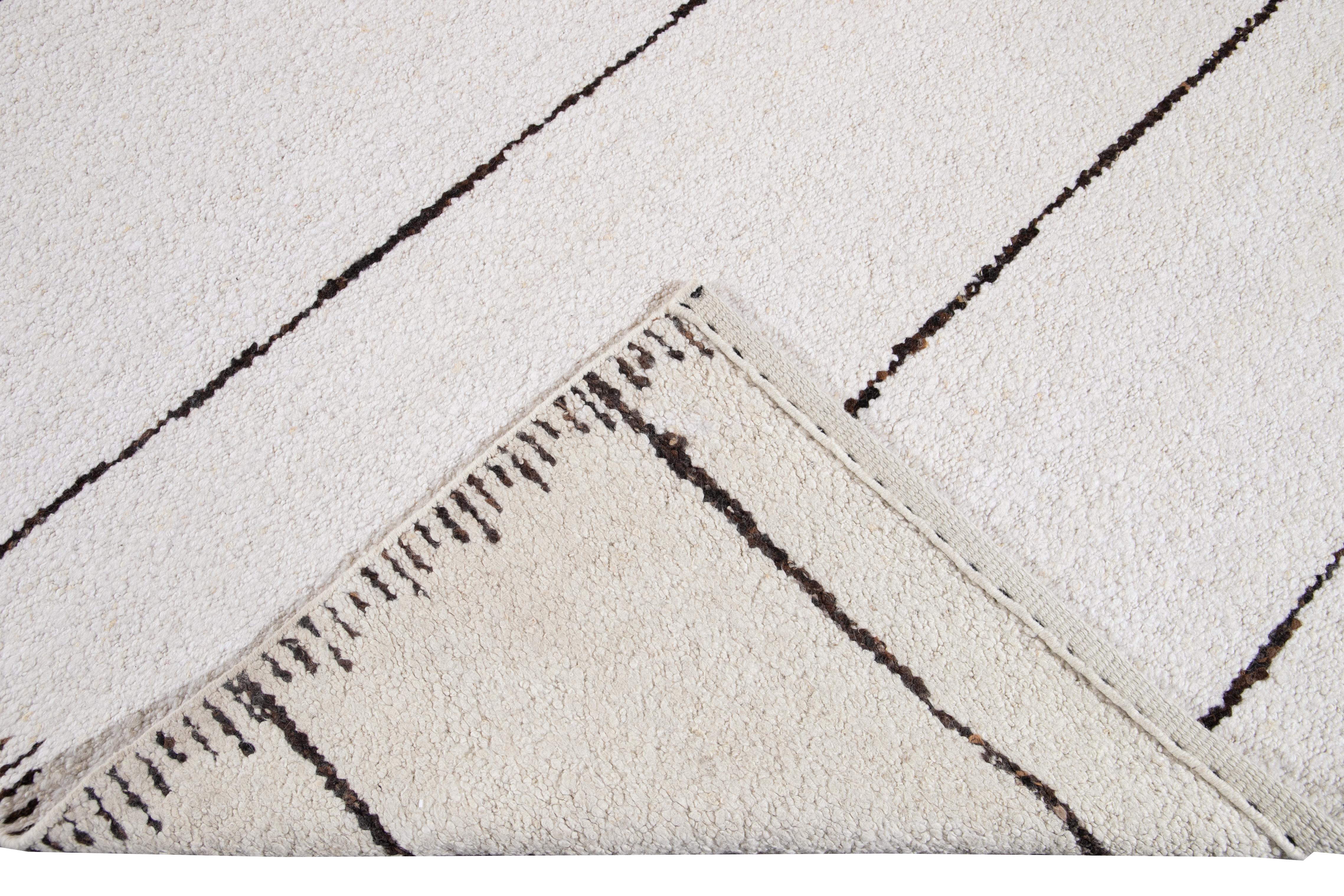 Beautiful Moroccan, style handmade wool rug with a white field. This Moroccan rug has accents in brown in a gorgeous all-over geometric striped design.

This rug measures: 12'5