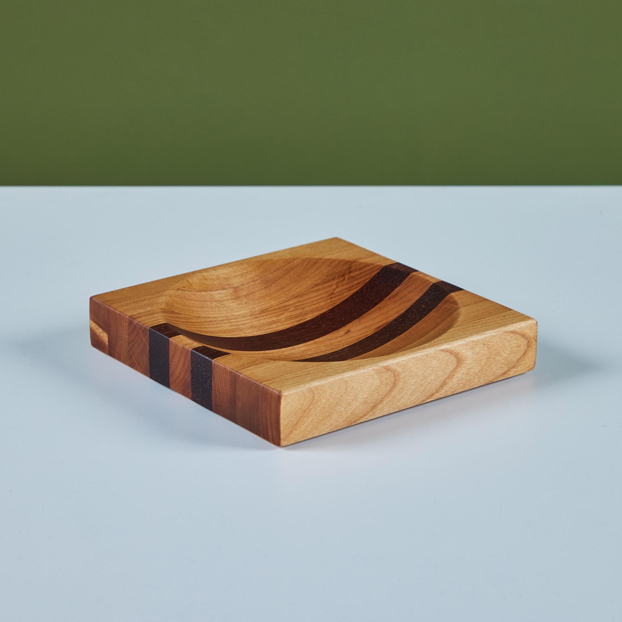 Square wood catchall in both oak and rosewood with a deep round center well. The dish showcases two darker stripes of rosewood down the center. A fun place to hold jewelry, keys or trinkets.

Dimensions
7.25