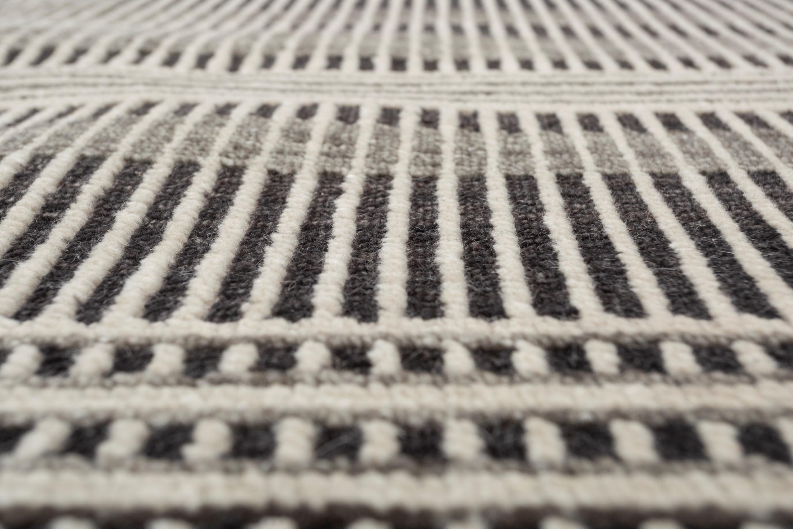 Avec son jeu de rayures de différentes largeurs et profondeurs, ce tapis moderne fait main crée une illusion visuelle dynamique et captivante. Les rayures passent sans transition par un subtil effet de dégradé, ce qui ajoute de la profondeur et de