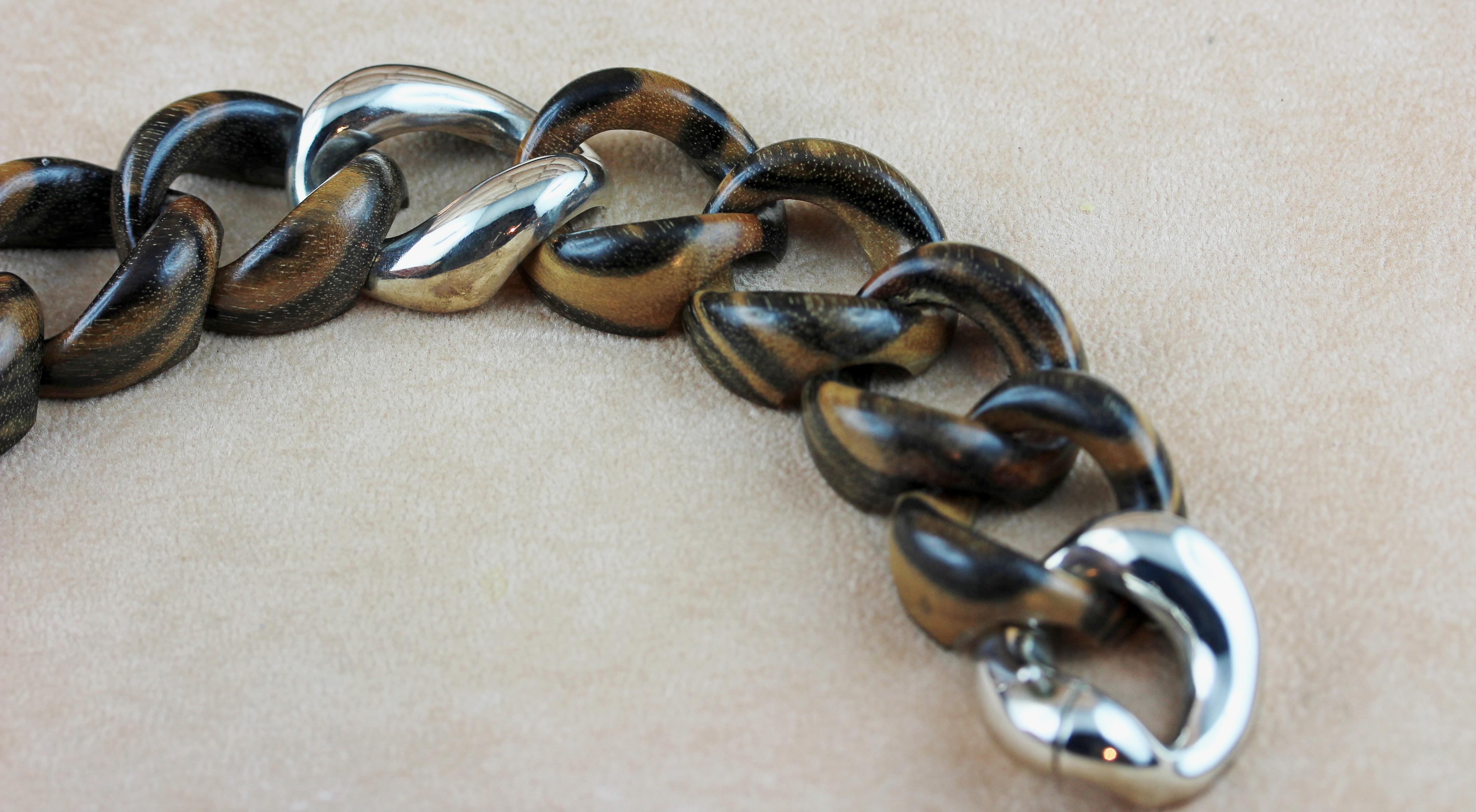 Dans cet élégant bracelet groumette, des anneaux en bois à rayures brunes sont agrémentés d'un anneau au centre, créant une allure contemporaine.
Le fermoir et  en argent 925. 
 
Dimensions :
                     21,5cm x 3 cm environ

Poids :
     