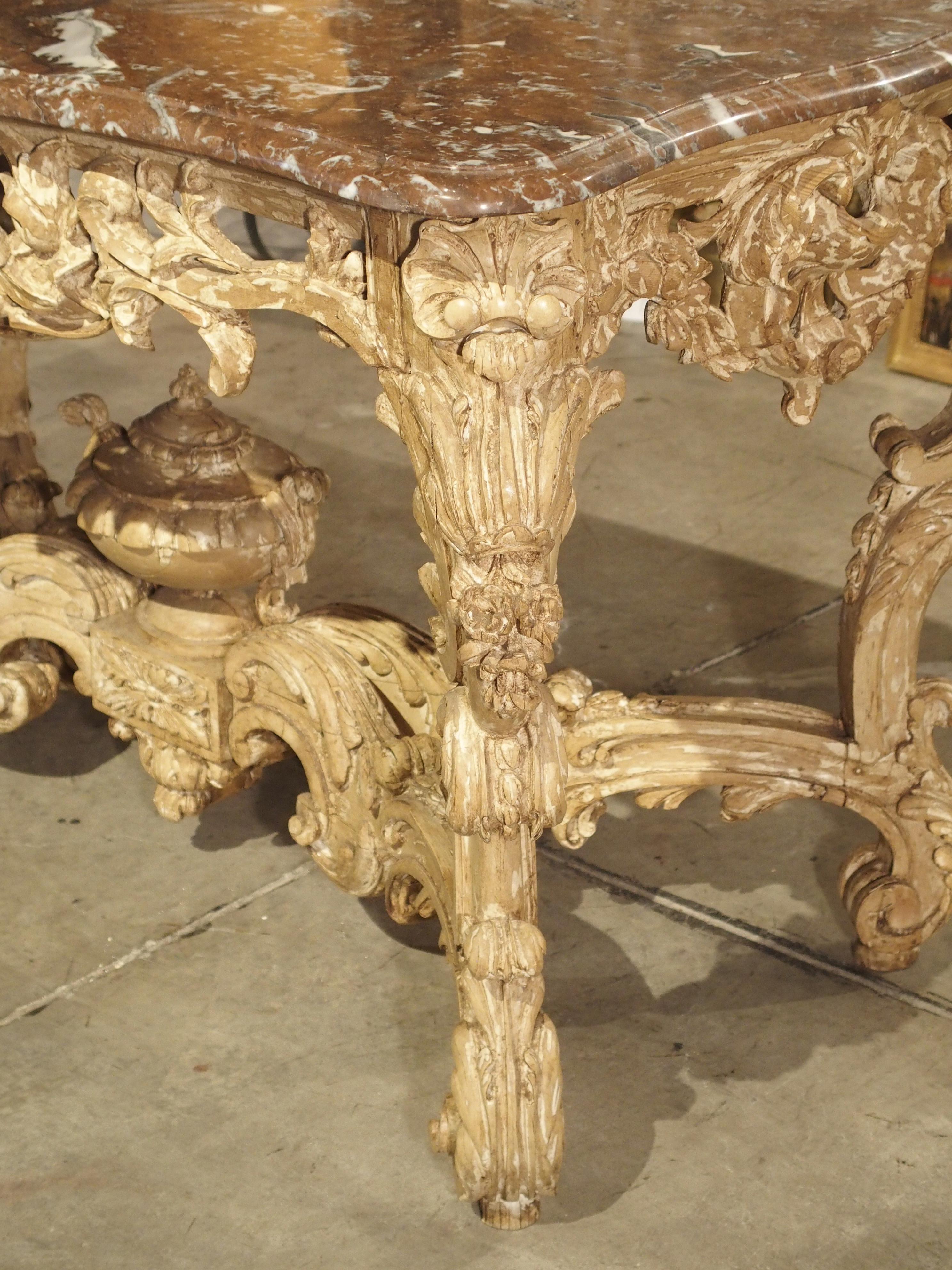 This elegant and beautifully carved wooden center table from France incorporates design elements from two of the most popular French periods.

The intricate hand carved base exhibits aspects of the Rococo style: highly ornamental with asymmetrical