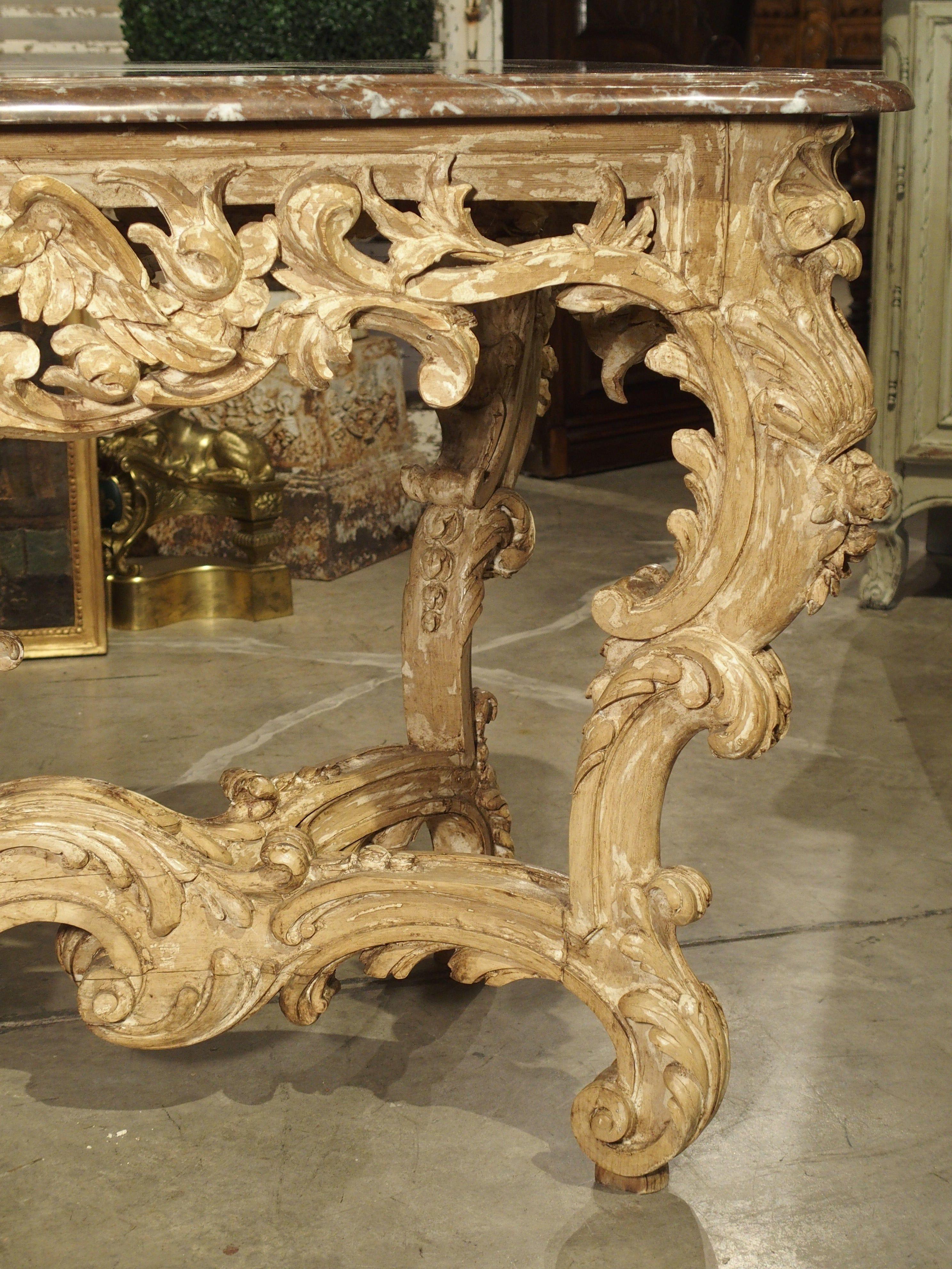 This elegant and beautifully carved wooden center table from France incorporates design elements from two of the most popular French periods.

The intricate hand-carved base exhibits aspects of the Rococo style: highly ornamental with asymmetrical