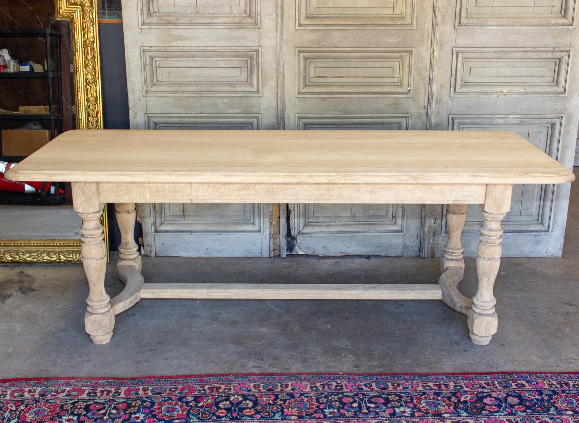This antique French oak table has turned details in the legs, with hand carved accents in the legs and stretcher-style base with gentle curves at each end, between legs. The top itself has a beveled edge and rounded corners. The legs are