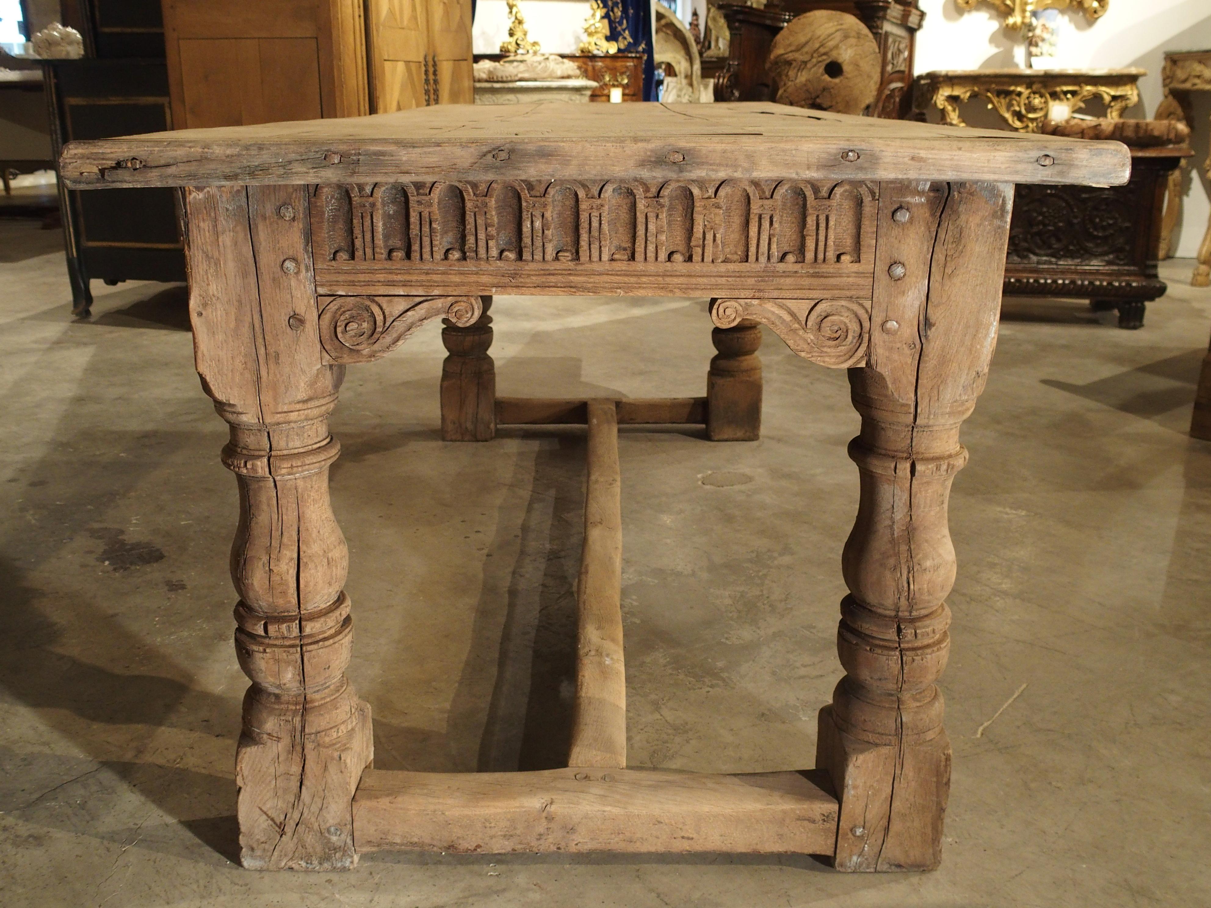 This robust oak table dates to circa 1880, and it is in the English Jacobean style (16th and 17th Centuries). It is considered a refectory table because of its relatively shallow rectangular form. The top consists of three long oak planks with