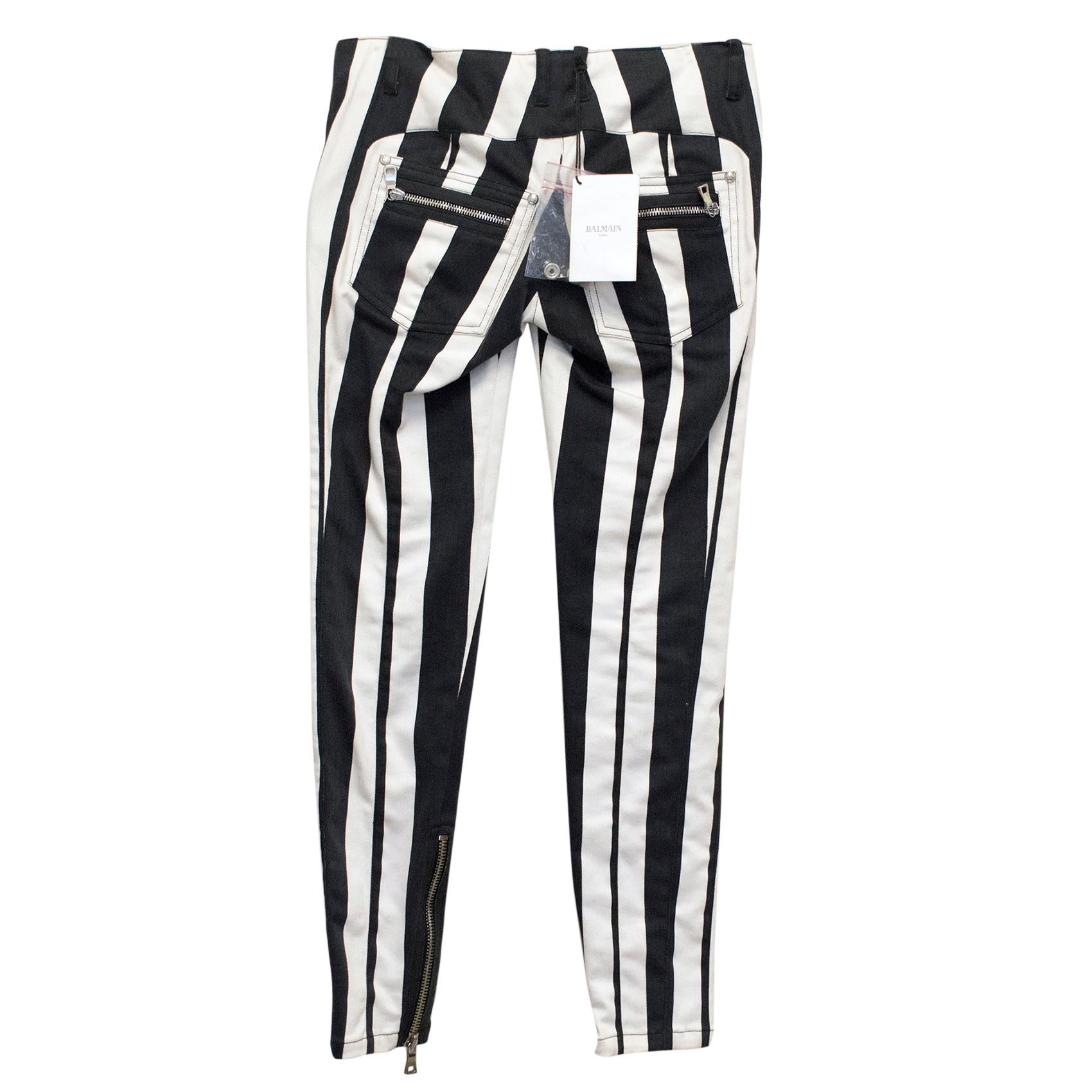 New black and white stripped Balmain skinny jeans. Silver buttons accent the belt loops, pockets, and front zipper closure. Zippers line the legs from the bottom hem on both sides, the 2 front, and the 2 back pockets. Comes with extra replacement