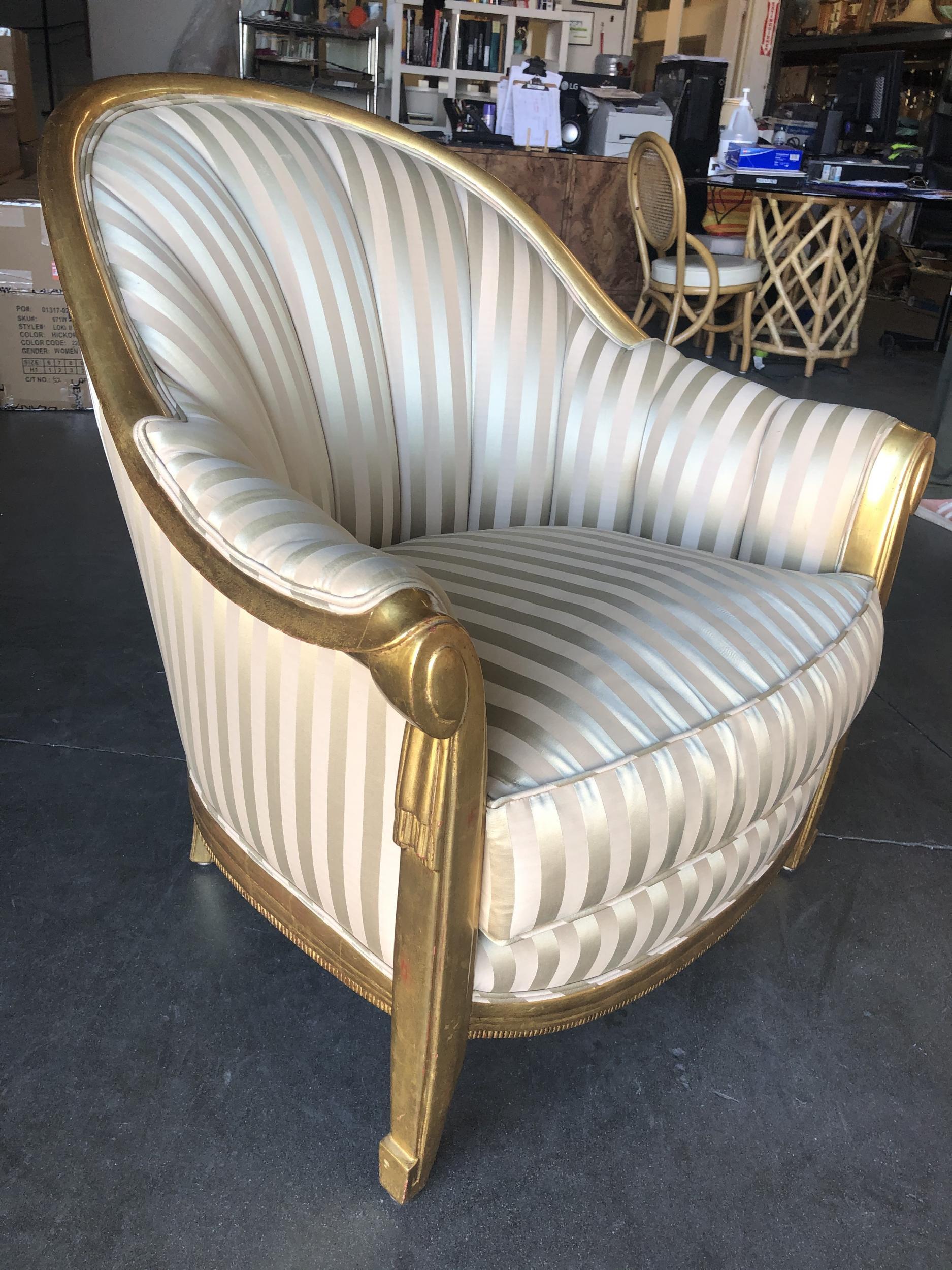 Hollywood Regency shell back lounge chair featuring a gold-painted frame with a cream-colored and silver striped covering.