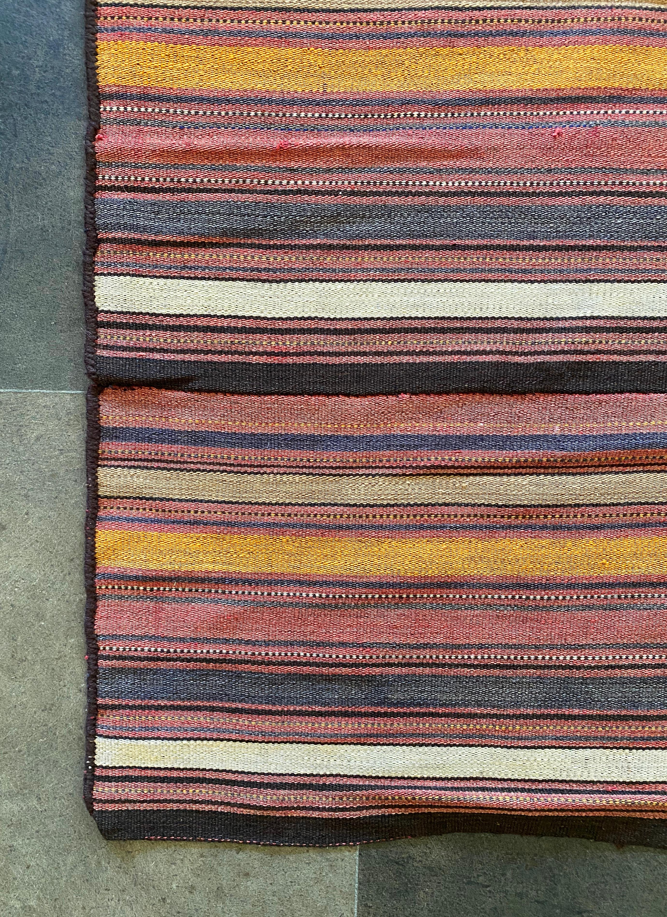 This Turkish Klim rug features a stunning mix of naturally dyed wool stripes in orange, red, black & cream pigment. It originates from the early 20th century. There is some age related fading to the original colour. 

Dimensions: Length 247cm x
