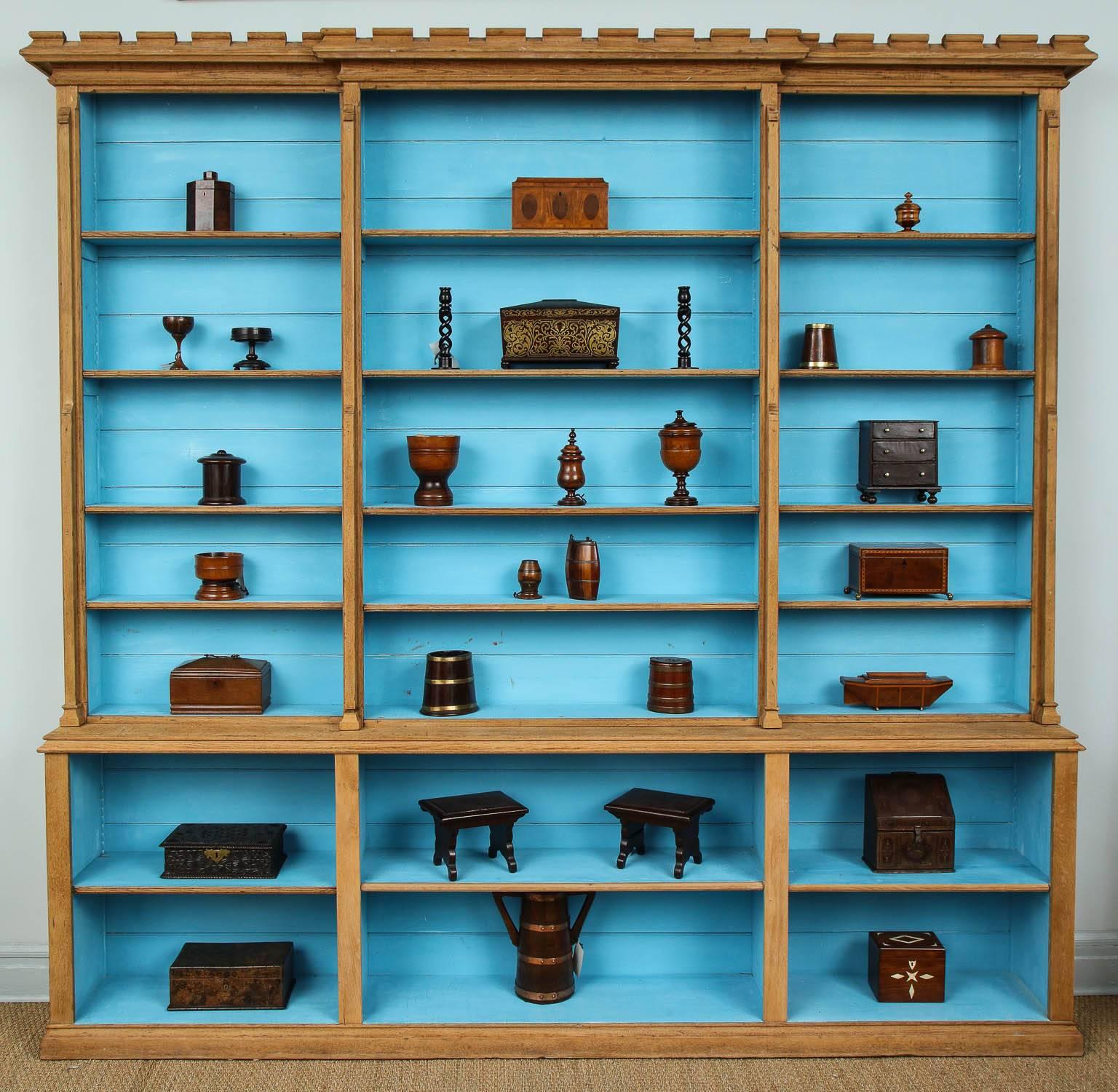 Very good 19th century English oak library bookcase, now with stripped surface and blue painted interior having crenellated cornice, with both upper and lower sections with adjustable and fixed shelves, the original backboards with bead molded edges.