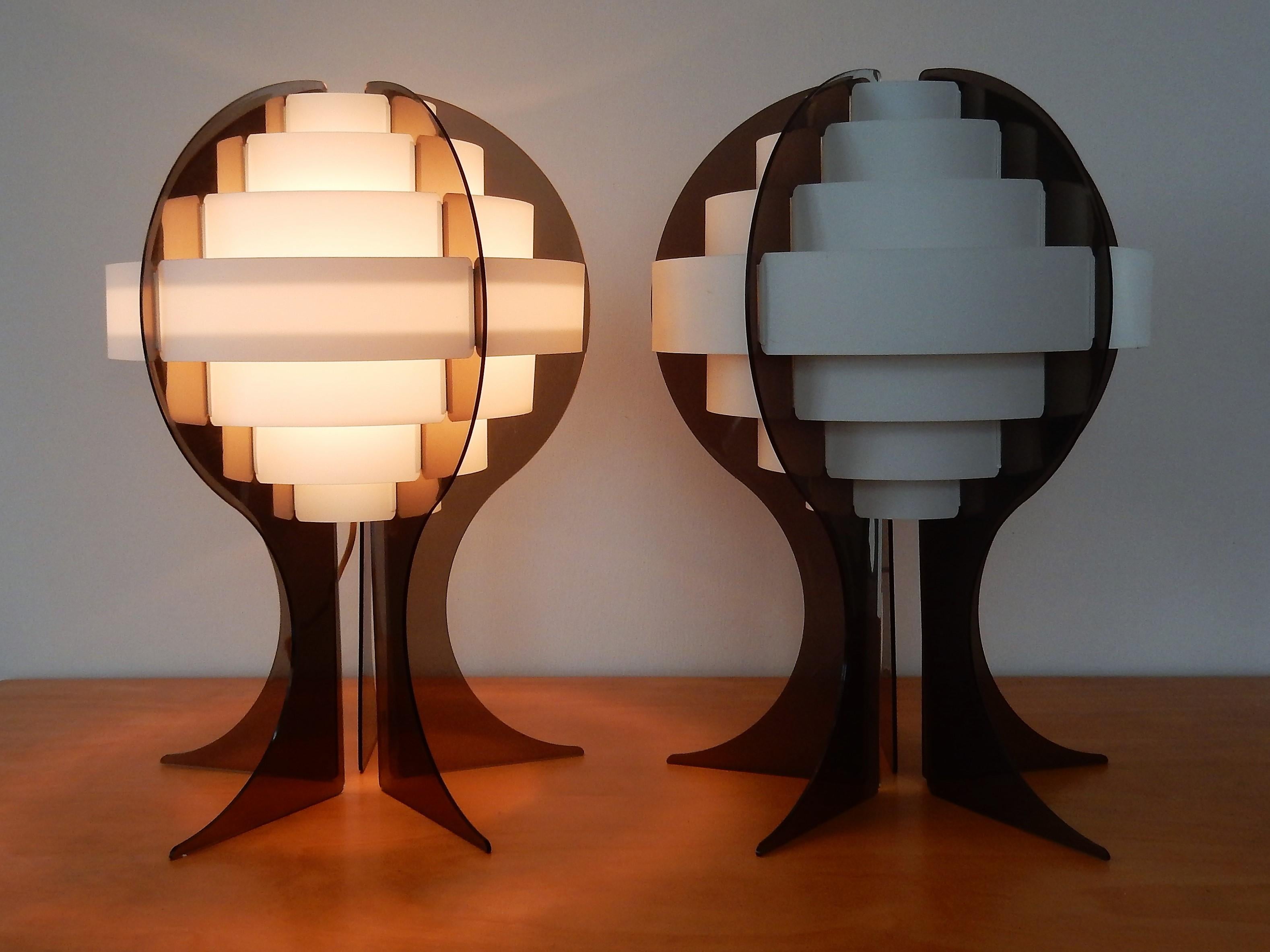 This 'Strips' table lamp was designed in the late 1960s-early 1970s by Preben Jacobsen & Flemming Brylle for Quality System in Denmark. It has a smokey grey acrylic base which supports a shade, made of white pvc rings (strips). Each ring overlaps
