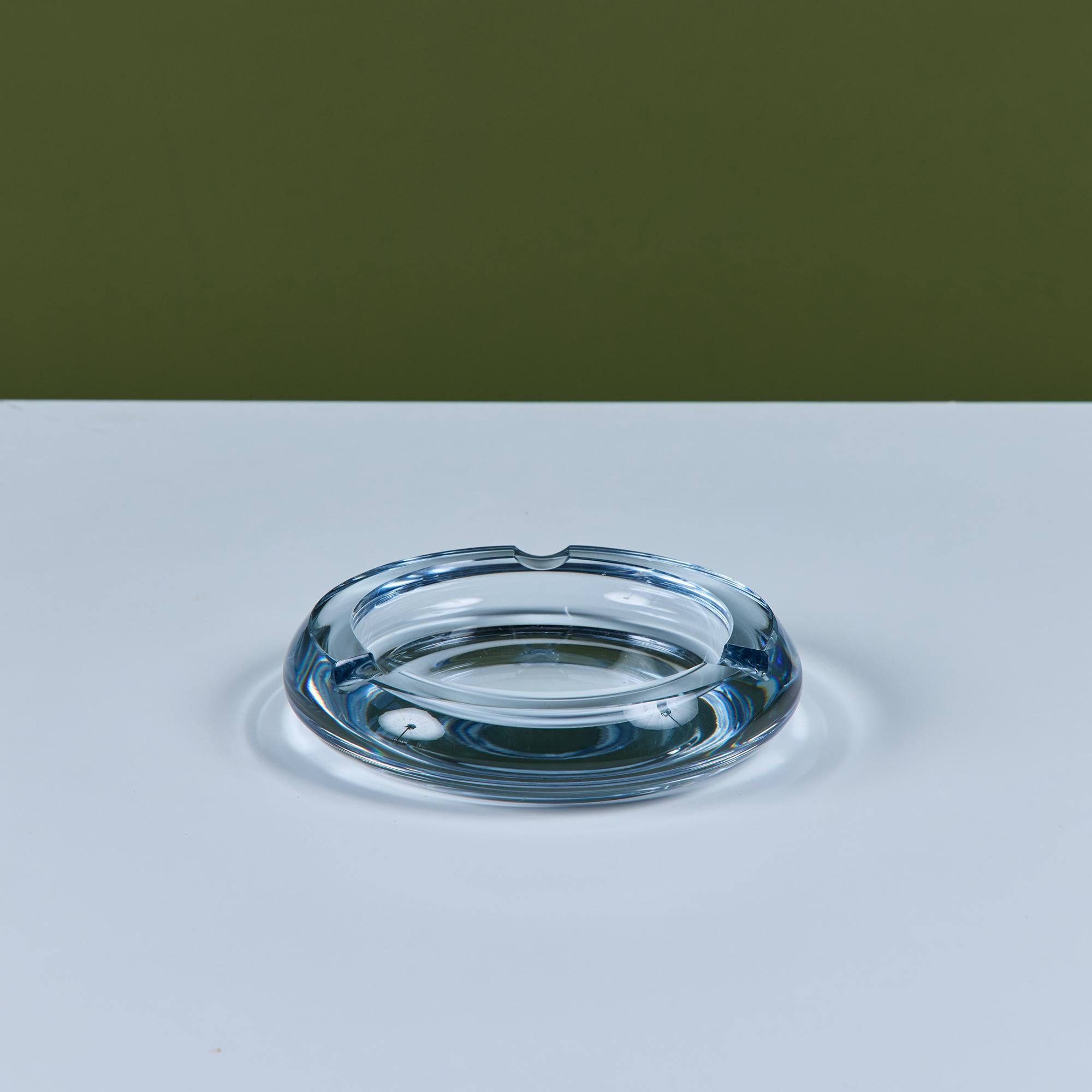 Glass ashtray by Swedish company Strömbergshyttan Glass, c.1960s. This piece, features a round clear thick glass with three notches and a deep well. Perfect for its intended use or as a minimalist catchall. 
Signed - Strömberg H8.

Dimensions
6.5