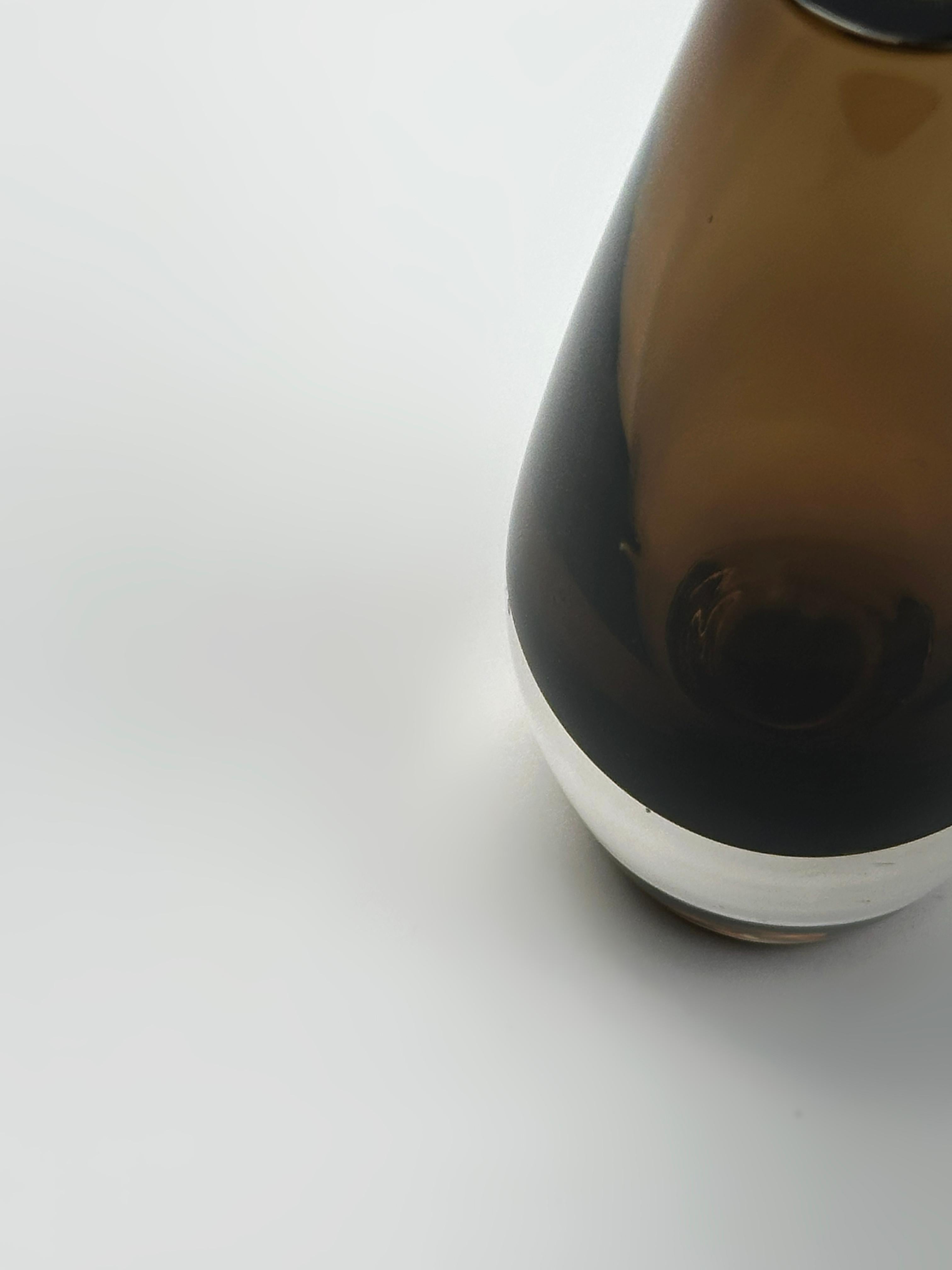 A small mid-century Swedish smoked glass bud vase by Strömbergshyttan. Modernist in style, the vase is crafted from thick-walled glass using the sommerso technique, with a layer of rich smoked brown encased in clear crystal.

The form is elegant in