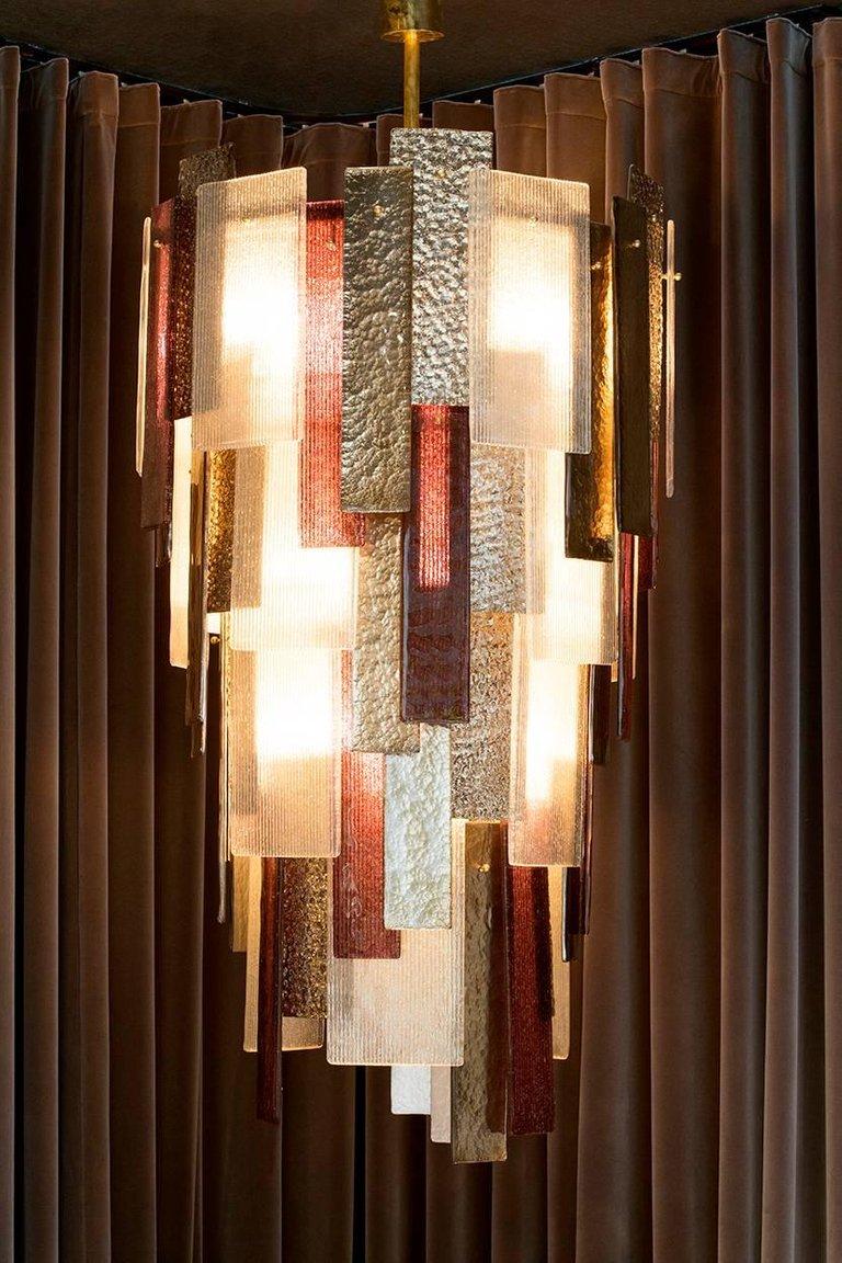 Ein monumentaler Kronleuchter, der die Vielseitigkeit von Murano-Glas demonstriert. Auf einem einfachen Rahmen aus lackiertem Stahl ist jedes Glas mit einem Messingstift befestigt, der das Glas über der Leuchte zu schweben scheint. Jedes Glasstück