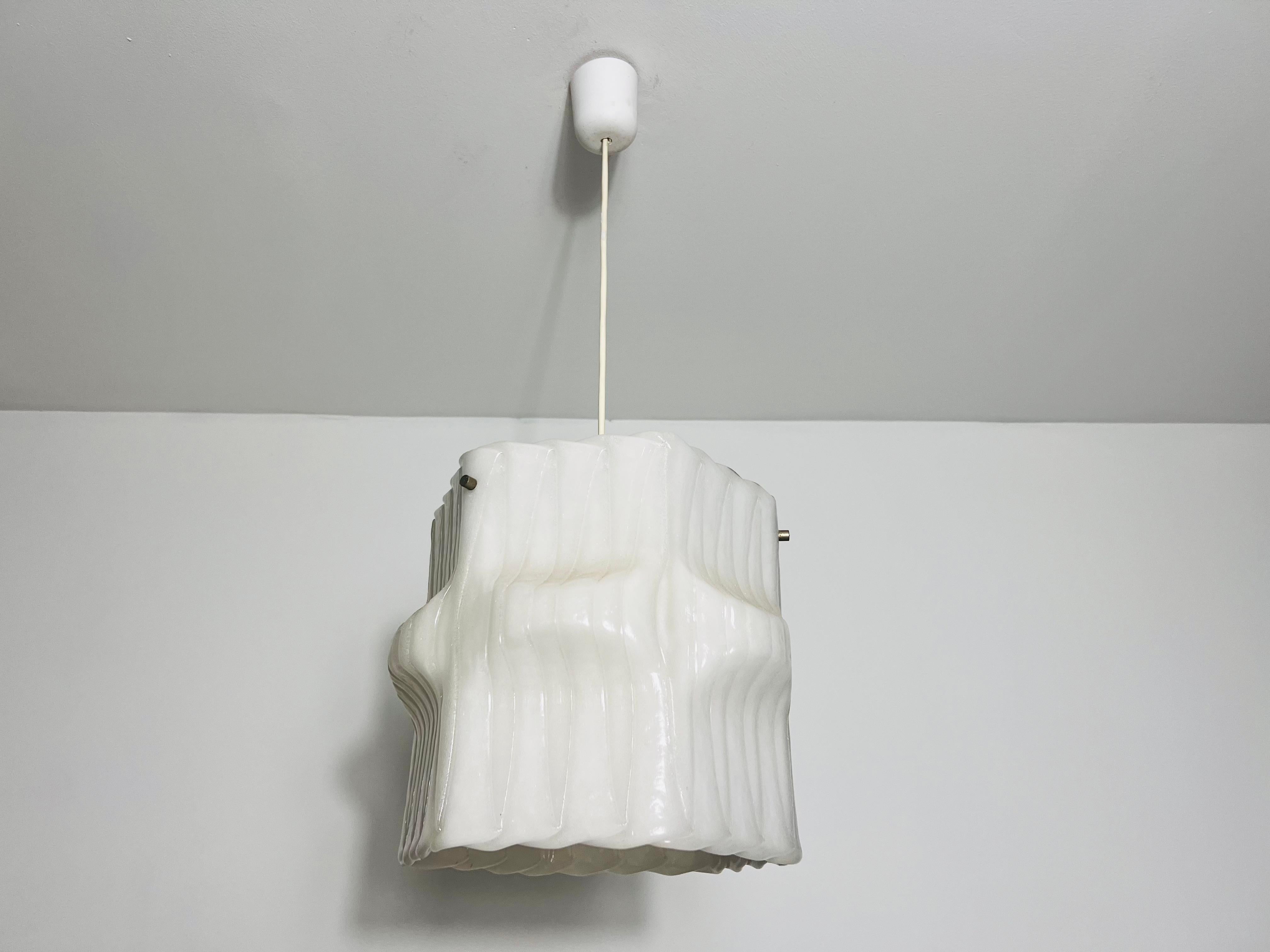 This white ceiling lamp from 1960s Germany is a striking example of minimalist design with a unique twist. Although crafted from durable plastic, its textured surface closely resembles frosted ice glass, giving the impression of real ice. The lamp’s