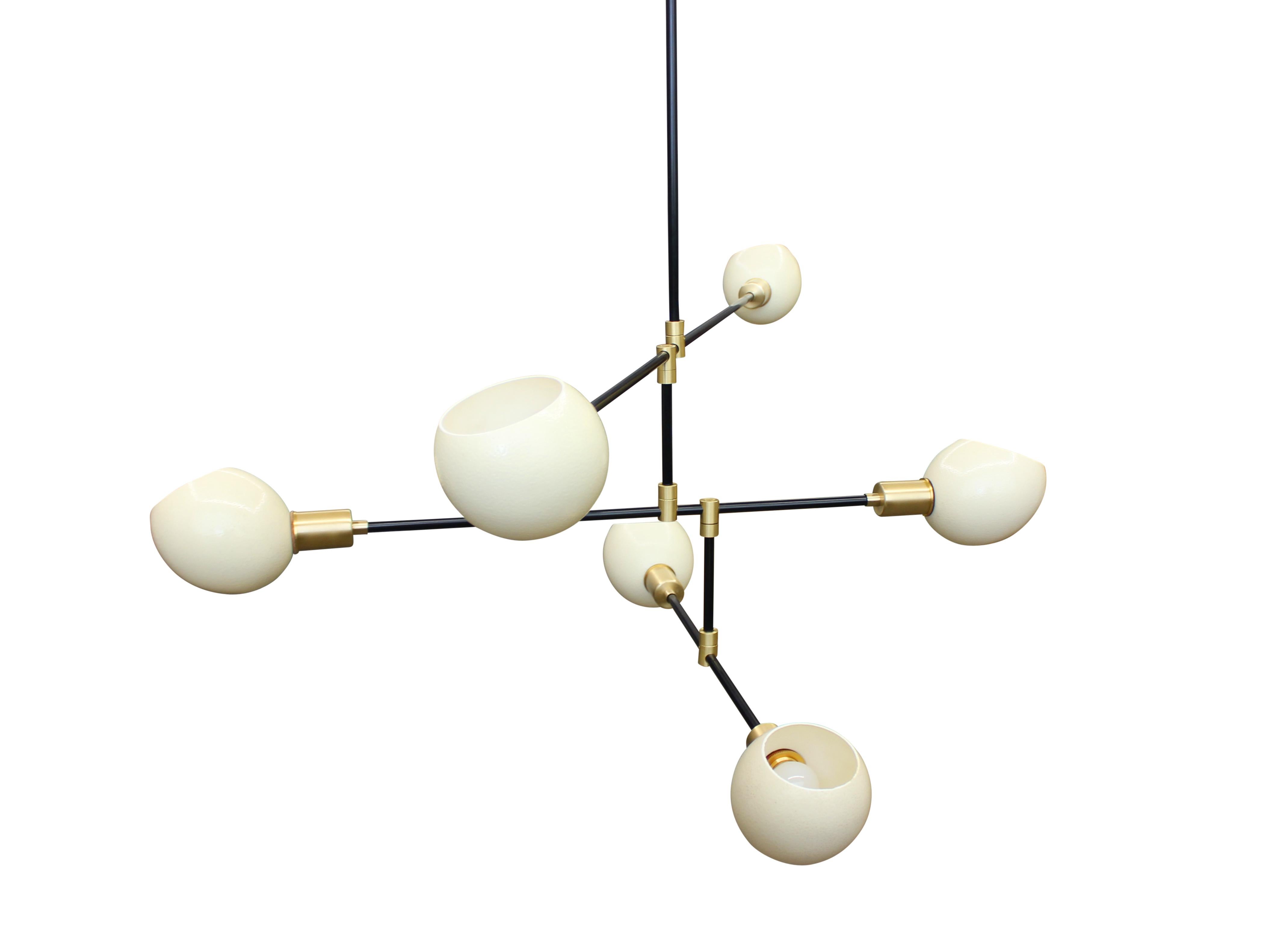 Six armed chandelier in blackened steel with brass fittings, featuring six bias cut natural ostrich egg diffusers. Adjustable arms can be arrayed at various angles. Can also be made as an eight or ten arm fixture.