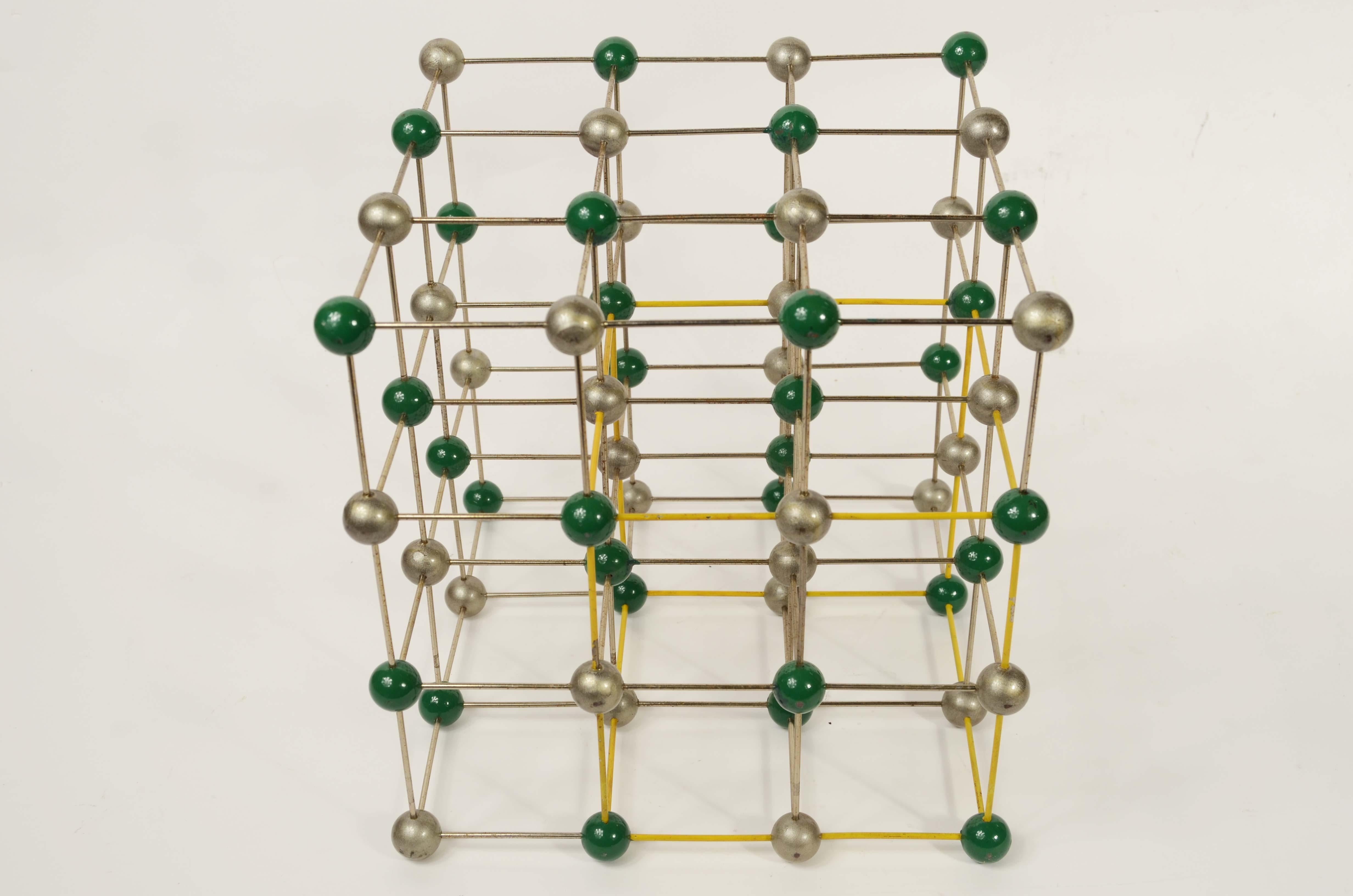 Struttura molecolare del sale, cloruro di sodio (NaCl) ad uso didattico in metallo satinato e verniciato giallo, sfere in bachelite verniciate verde e grigio. 
Buono stato. Misure cm 24,2x24,2x24,2- 9.5x9.5x9.5 inches.
L'ultima foto è la confezione