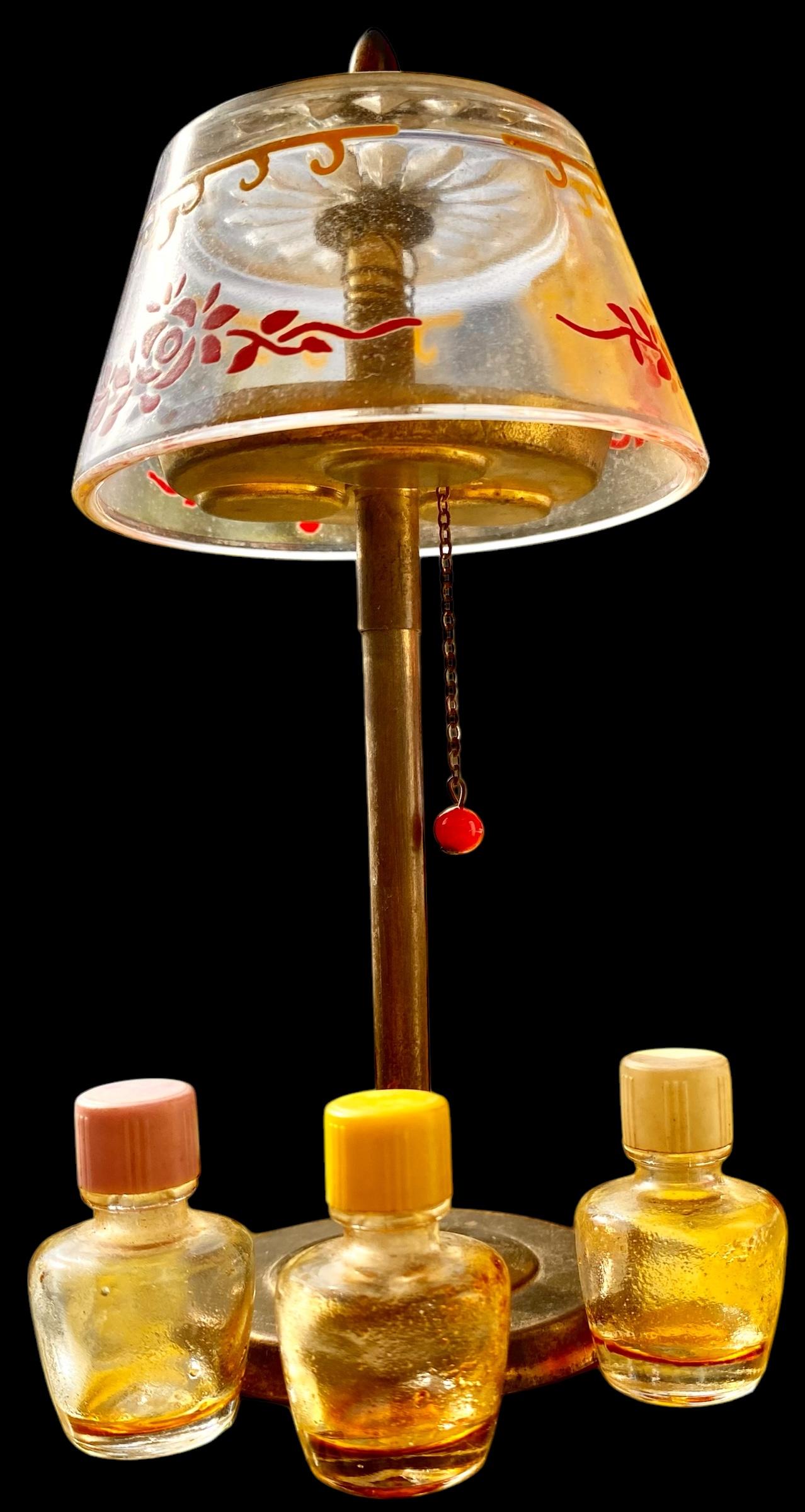 La lámpara es de latón con una cadena de tracción de la pantalla de latón accionada por resorte.
La pantalla es de cristal y está pintada con un dibujo amarillo y rojo.
La cadena baja la base de los frascos de perfume para que puedas acceder a los 3