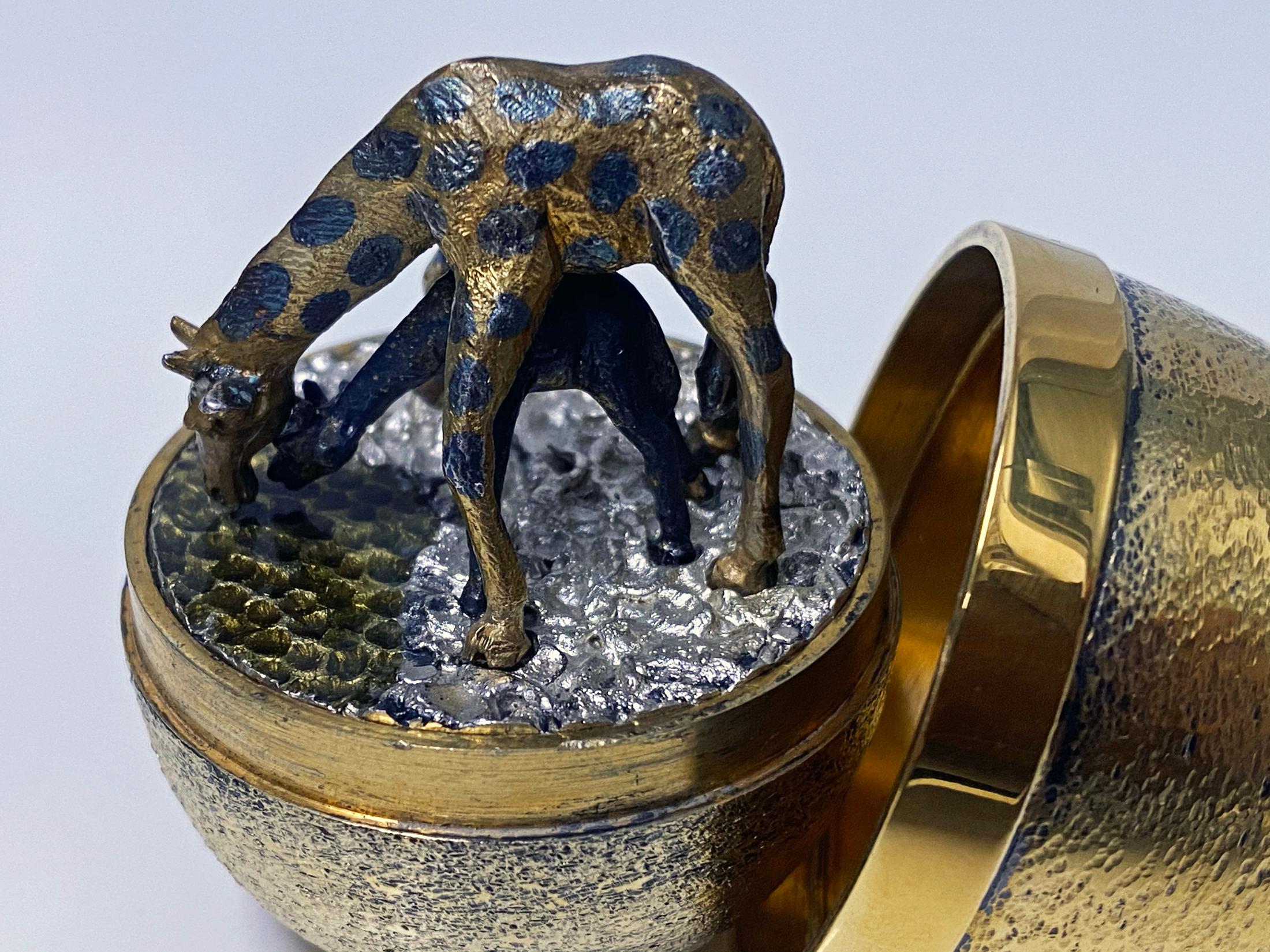 Rare Stuart Devlin silver and enamel egg London 1976. The top lifts off to reveal a giraffe and baby bending down to drink. The giraffes are made in silver and have been gilded and enamelled and they stand on a textured silver and enamelled base.