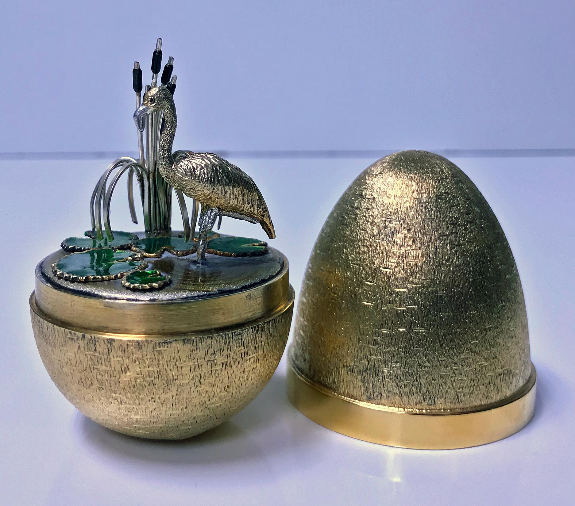 Stuart Devlin silver gilt surprise egg, London, 1983, opening to reveal a flamingo standing on a enamelled watery base with lily pads in front and bull rushes to one side. Original box and papers. Height 7.5cm high, No 19 of limited edition of 100.