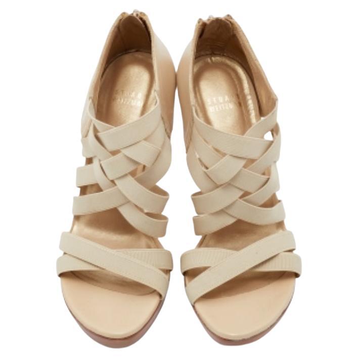 Ces sandales Stuart Weitzman apporteront une touche chic à votre tenue. Elles sont créées à partir de cuir crème et de tissu élastique, enrichi de brides croisées, de fermetures zippées dorées sur les contreforts et de semelles compensées. Ils sont