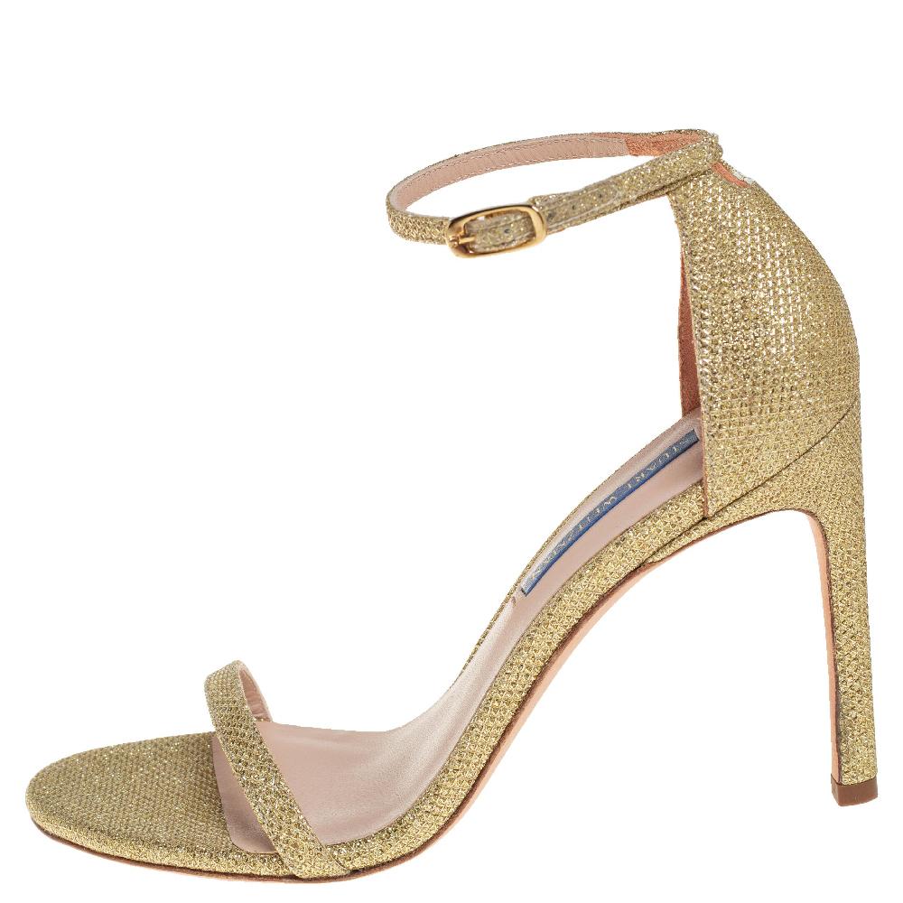 These timeless and graceful Stuart Weitzman sandals are stunning. Crafted from glitter, they come in a dazzling shade of gold. They are styled with open toes, thin vamps, buckled ankle straps, covered counters, and 10 cm heels. They are finished