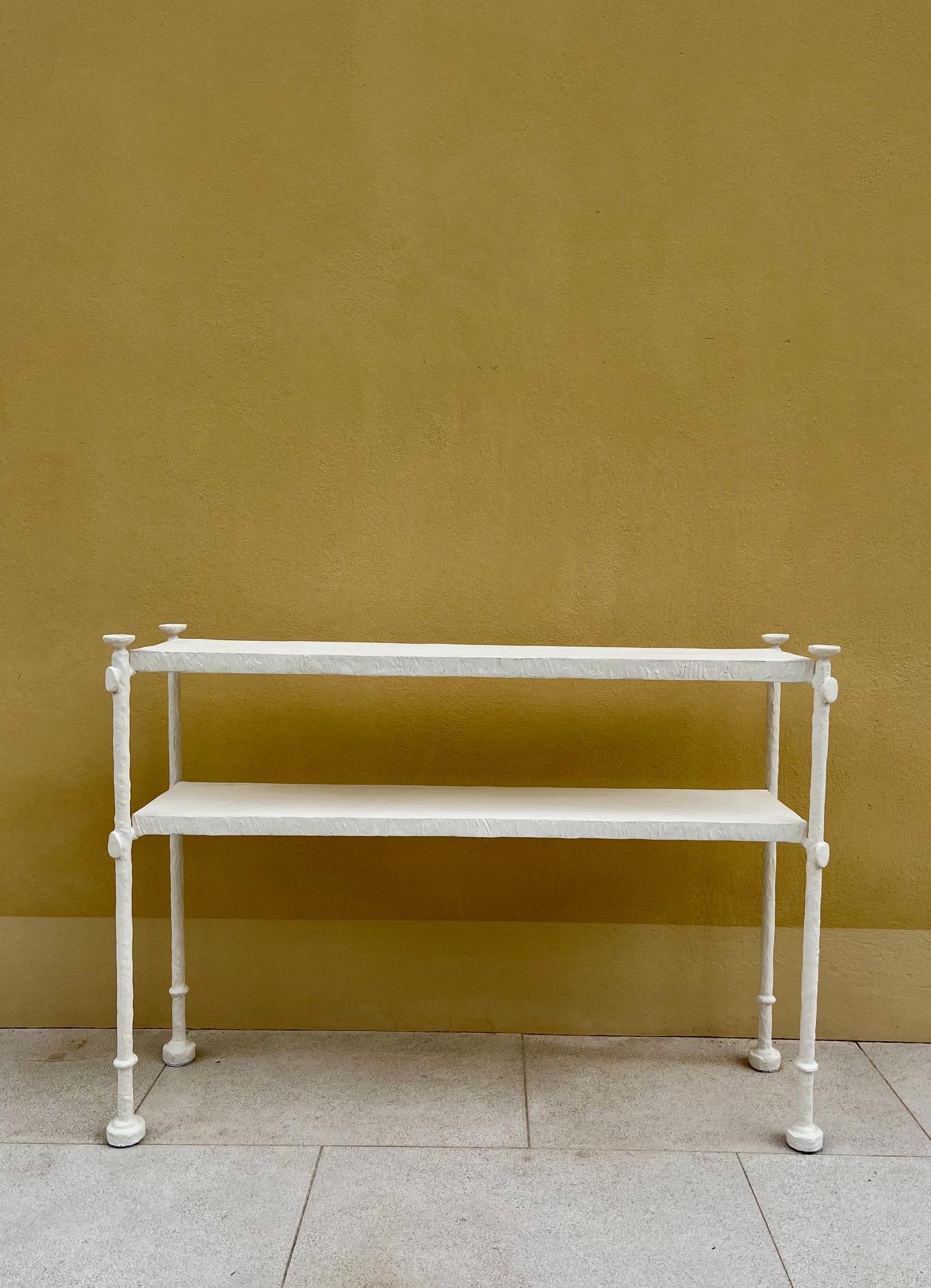 Elegante console en plâtre.
Console à deux niveaux, le haut de chaque pied étant terminé par une coupe piedouche. 

Plâtre stuqué sur structure métallique 
Inspiré par le goût néoclassique et plus particulièrement par le design des meubles d'Alberto