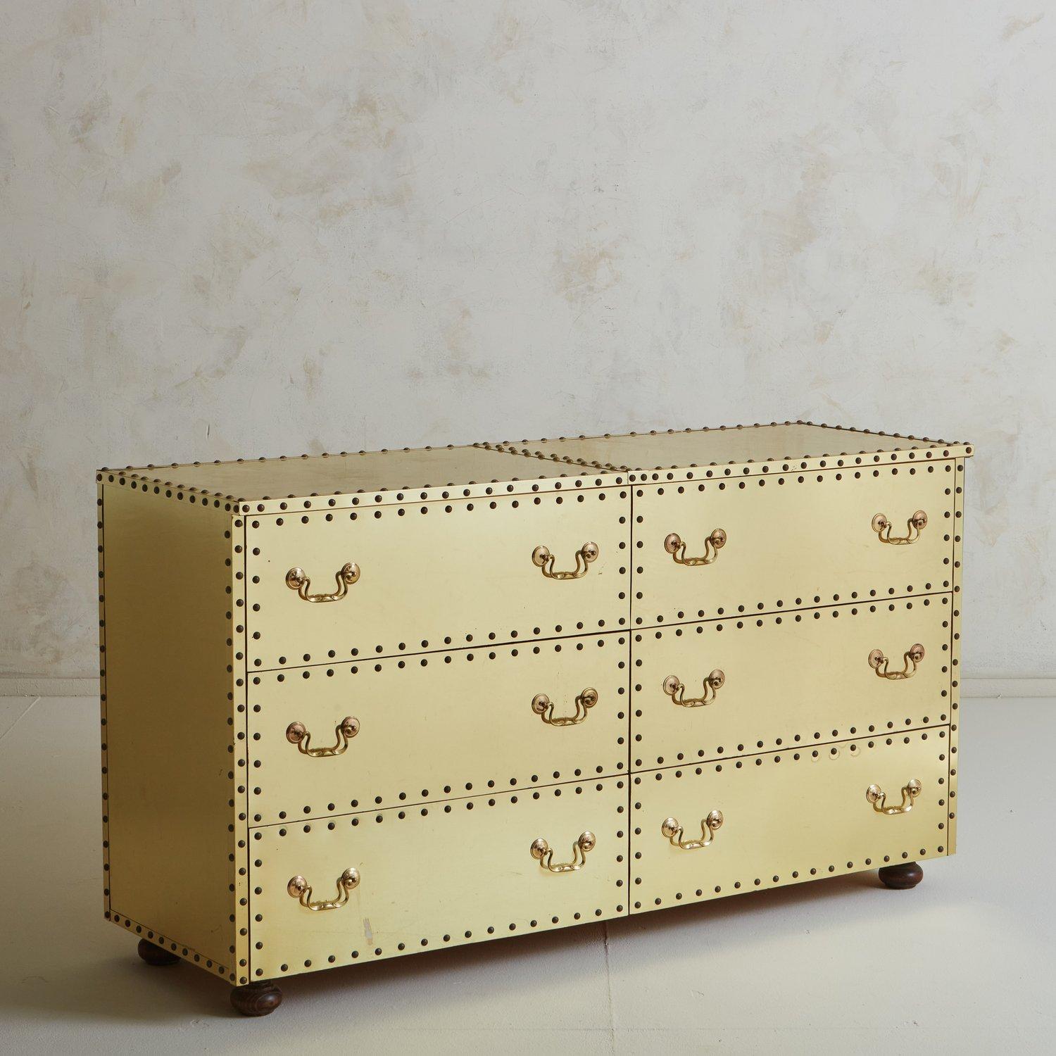 A vintage dresser clad in brass with beautiful stud detailing and brass hardware. This piece has six drawers, offering ample storage space. It stands on four oval wooden feet and has a wood backing. 20th Century.