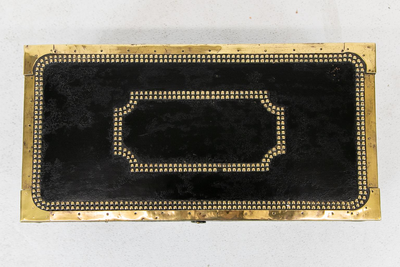 Studded leather camphor wood box has the original paper lining. The piece is black leather banded with brass, and it has a double row of brass stud work.