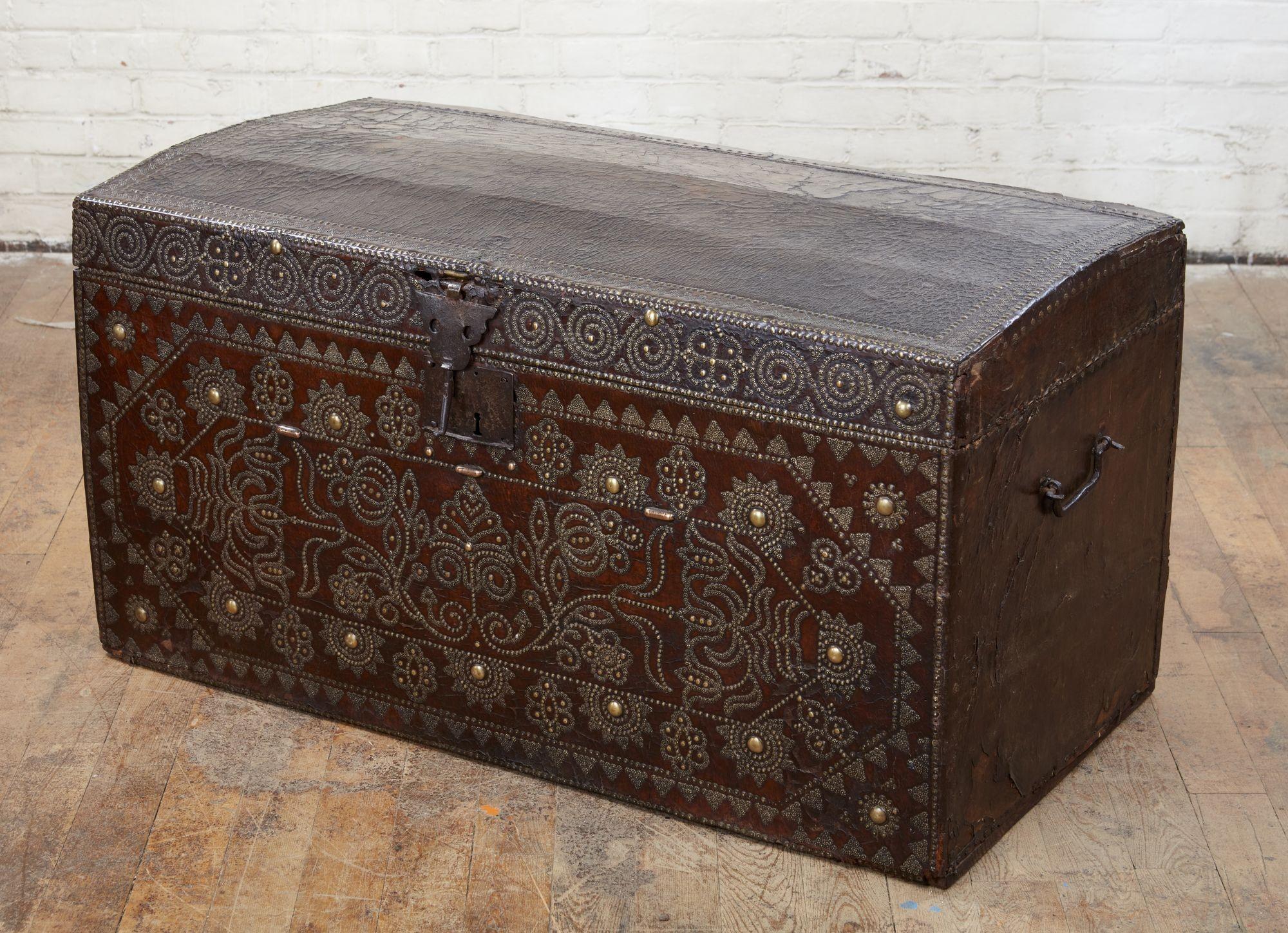Very fine early 18th century leather travel chest or trunk in beautiful brass and iron studded Spanish leather, having elaborate geometric floral design, the slightly domed top with thin border over profusely studded front with arabesque border,