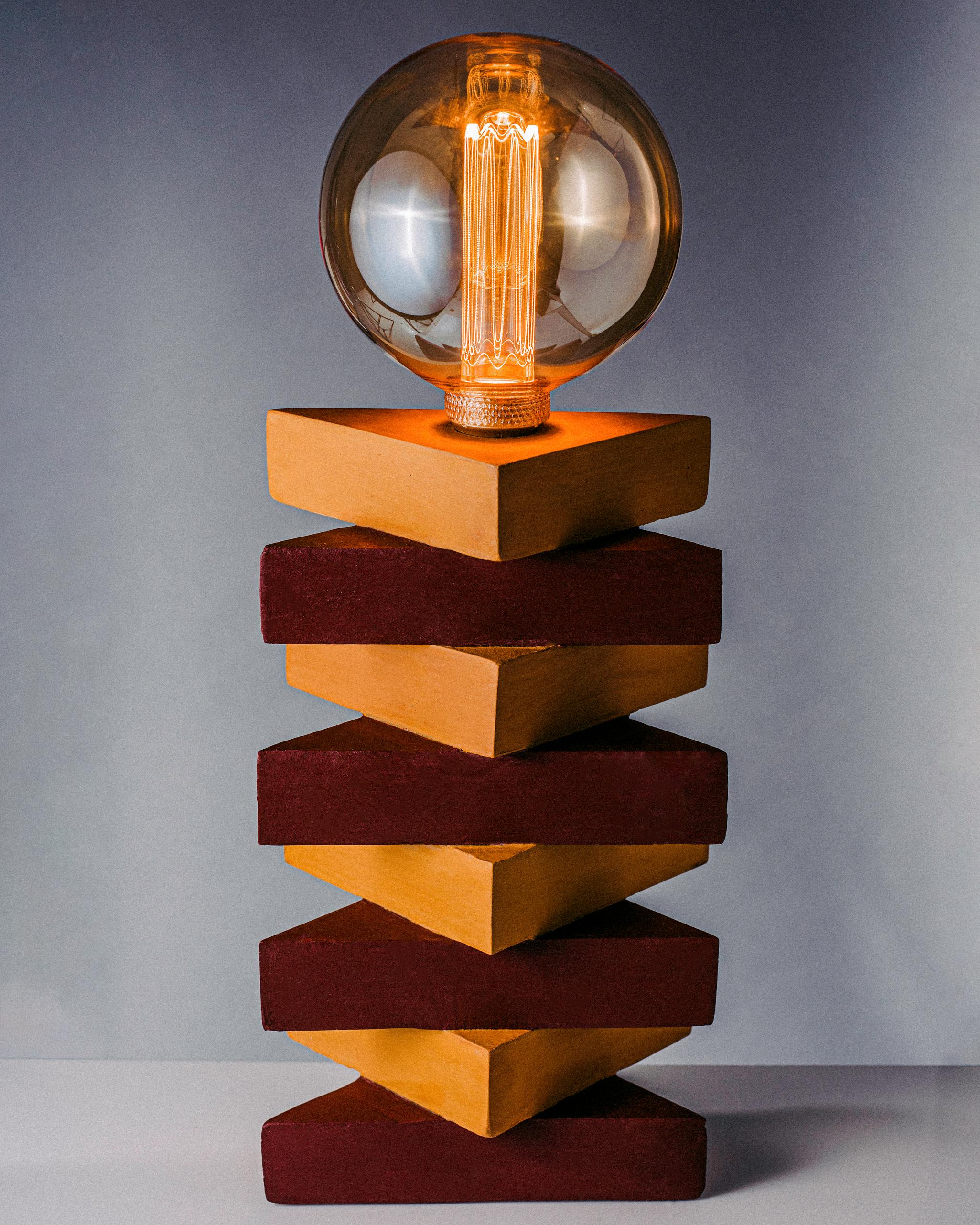 Vertical & elongated. A subtle little table inspired by the verticality of life. Alternating brown and goldenrod triangular wooden pieces create the base of this tiny but mighty table lamp. A modern lamp in a vintage style, to give it that found but