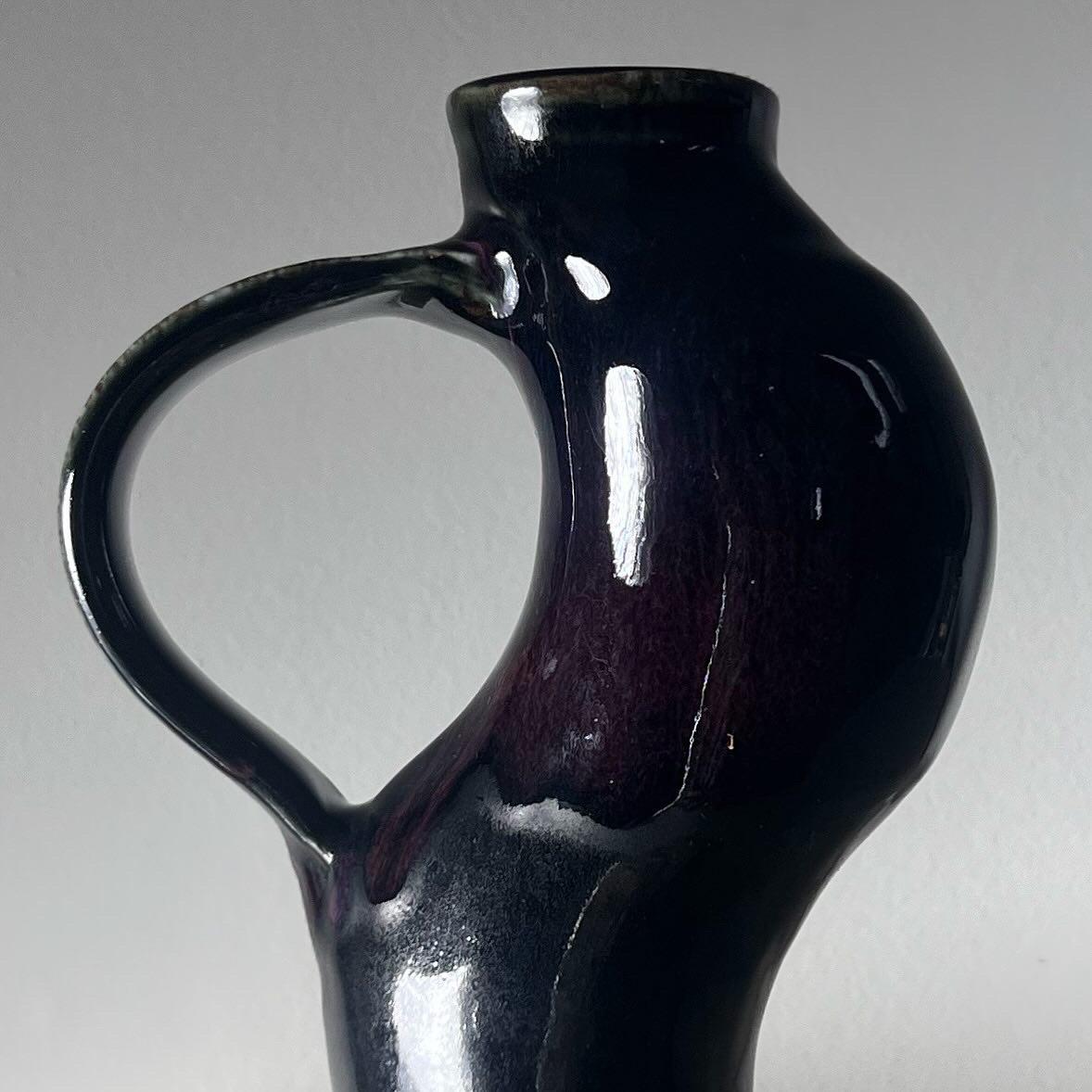 A unique studio art ceramic vessel featuring an unusual bombastic contrapposto stance with bulging belly, signed, early aughts. In deep licorice with hints of iridescent aubergine and lichen grace au glaze. Great condition. Pick up in central west