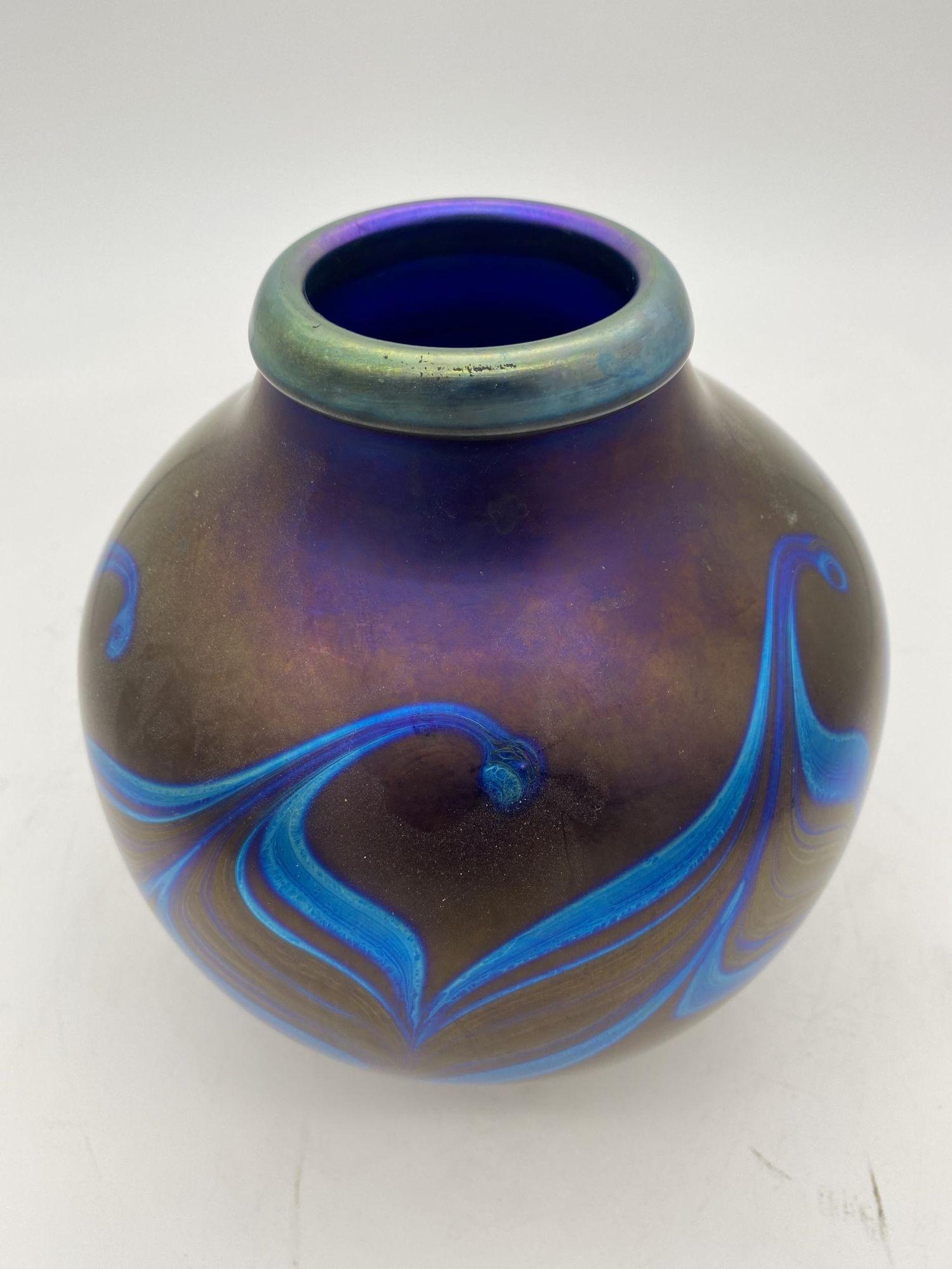 Lundberg Studios Blue Iridescent California Art Glass Vase with a Wave Pattern.

Lundberg Studios is located in the small coastal town of Davenport, California began in the backyard hot shop of James Lundberg, in 1970 with became a studio of master