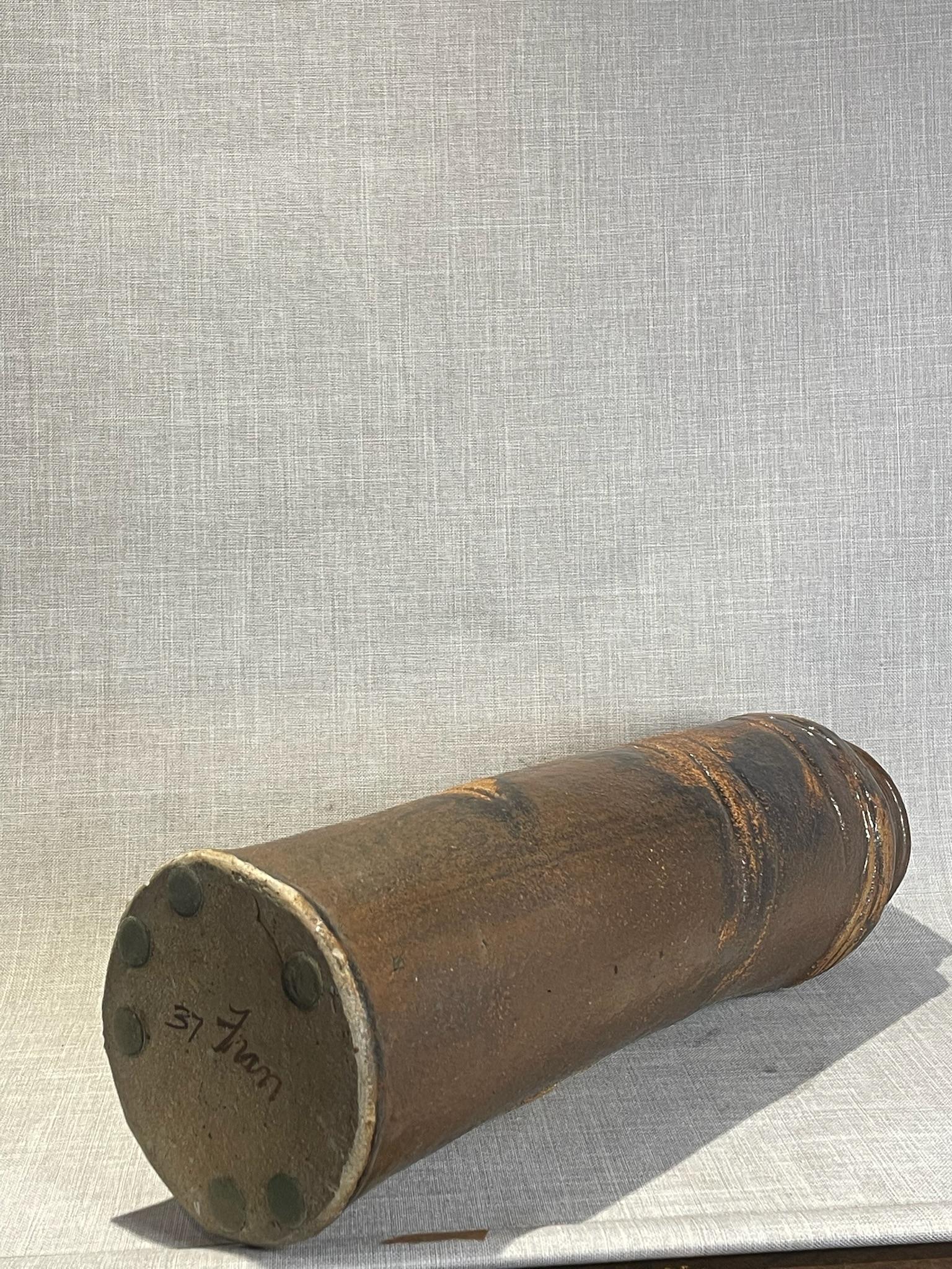 Questo vaso alto in Studio Pottery, realizzato a mano, presenta un'irresistibile miscela di texture rustica e arte scultorea. La forma cilindrica, con il suo contorno leggermente irregolare e il bordo ispessito, è rifinita con un ricco smalto