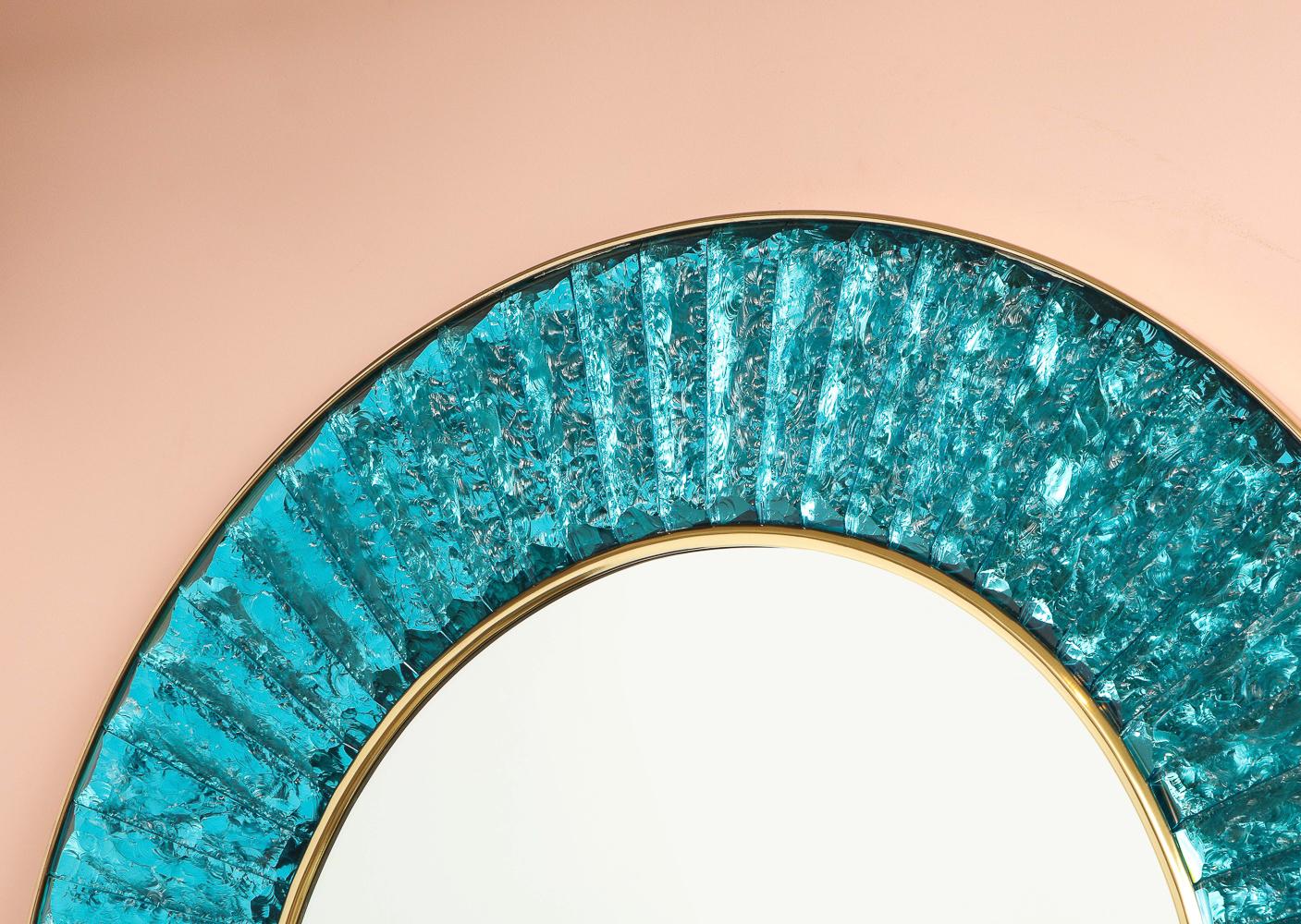 Contemporary wall mirror of hand-cut and chipped chunks of turquoise green glass. Arranged in a circle around a central mirror with brass mounts. Beautiful studio-made piece created exclusively for Donzella. Signed on side edge.