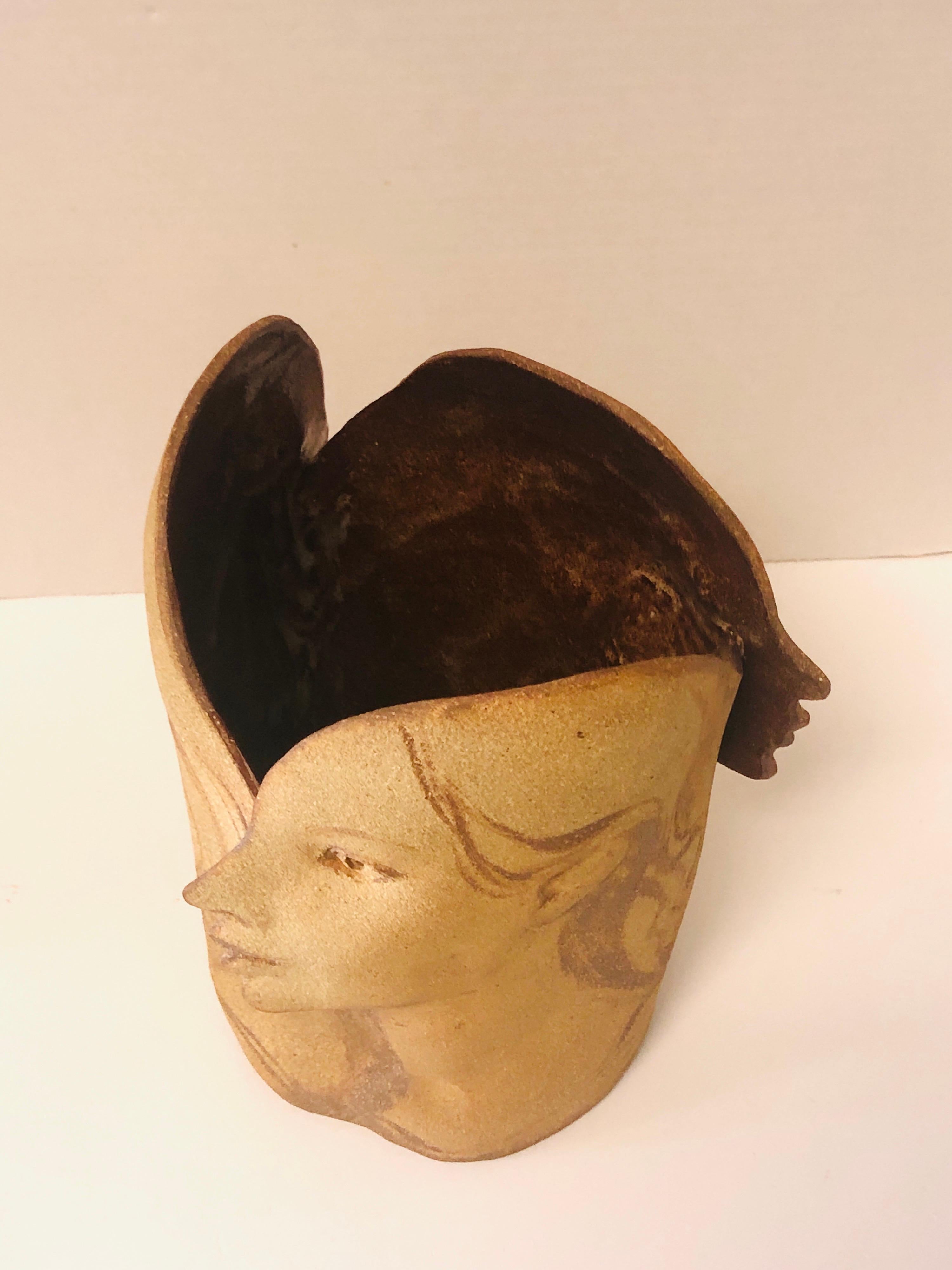 Exquisite vessel. Note the subtle sculpted features and brushstrokes. The surface of the faces is not flat just enough modulation of the planes to get a naturalistic feel without making the piece a literal representation of the subject. Apparently