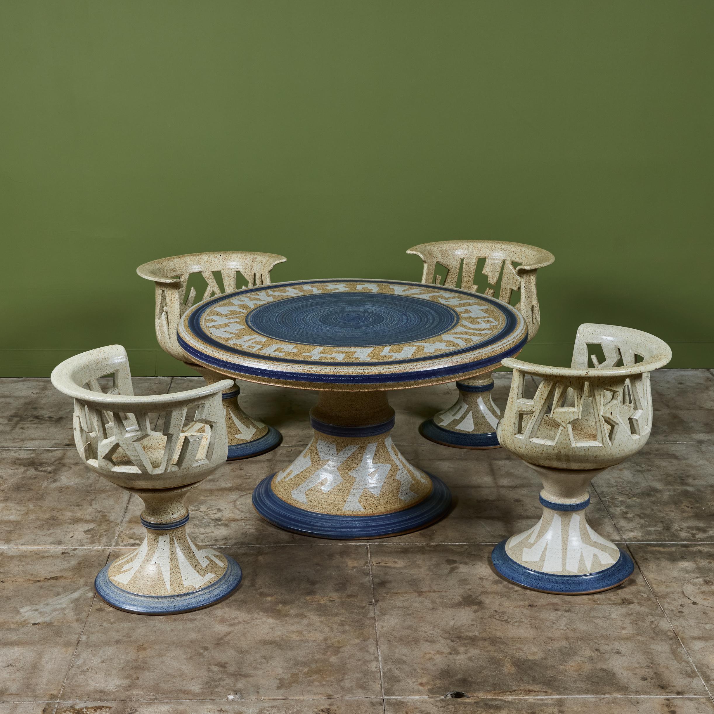 Outdoor studio ceramic patio dining set by ceramicist Joel Cottet, c.1970s. The set features four ceramic swivel chairs with a cutout seat back. The round pedestal table showcases a glazed table top with a blue center and design around the rim that