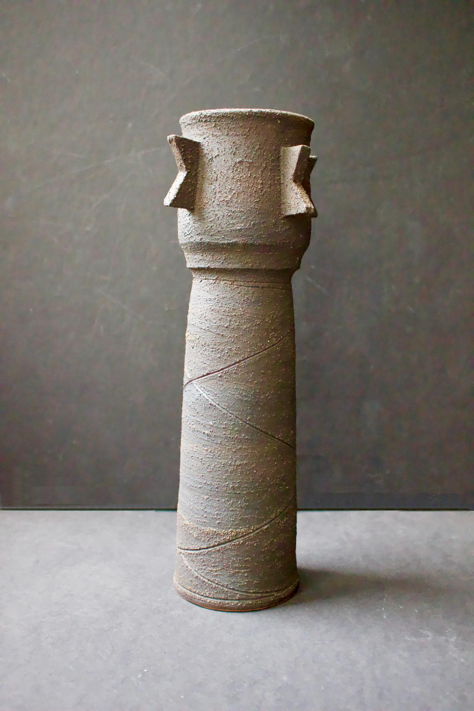 Studio pottery ceramic sculpture or vessel by Clive Brooker, England, 1960s.

Handmade ceramic, with strong silhouette and brutalist feel. The outer surface is charcoal in color, deep grey/brown, with matte finish and the texture of sand, with
