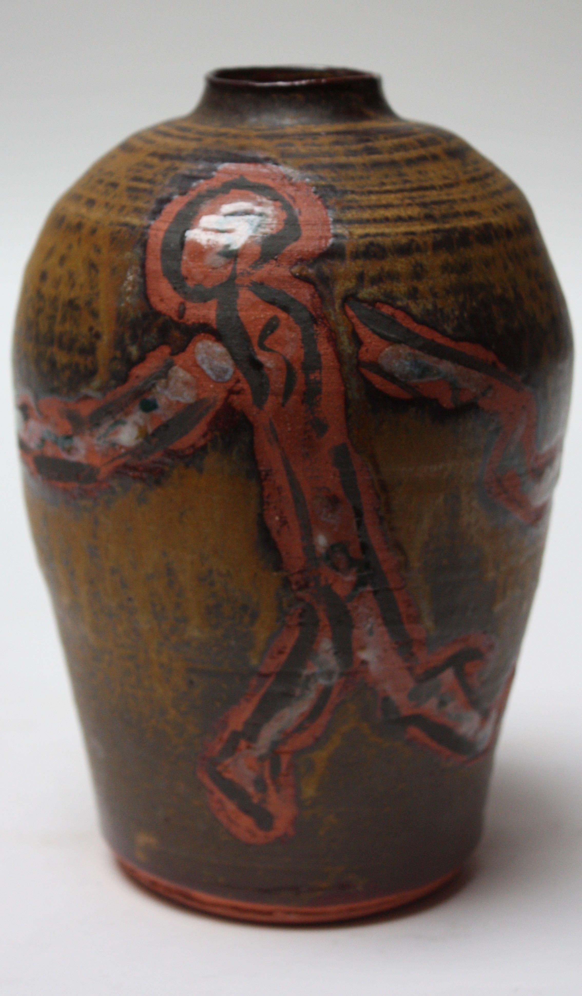 American Studio Pottery work featuring a hand painted Primitive figure motif on terracotta, circa 1970s. Attractive combinations of colors; the ochre and brown background contrast nicely with the terracotta, red, and green details of the figures