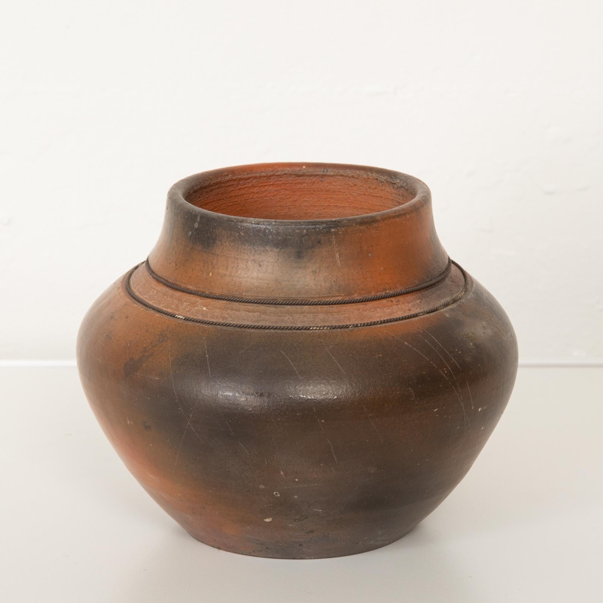 Studio ceramic vessel with Raku glaze. This wheel thrown vase features a bright orange-toned matte Raku glaze with black accents. Detailed with two textured striated lines around the neck. 
Signed on the underside with the maker's mark. Dated
