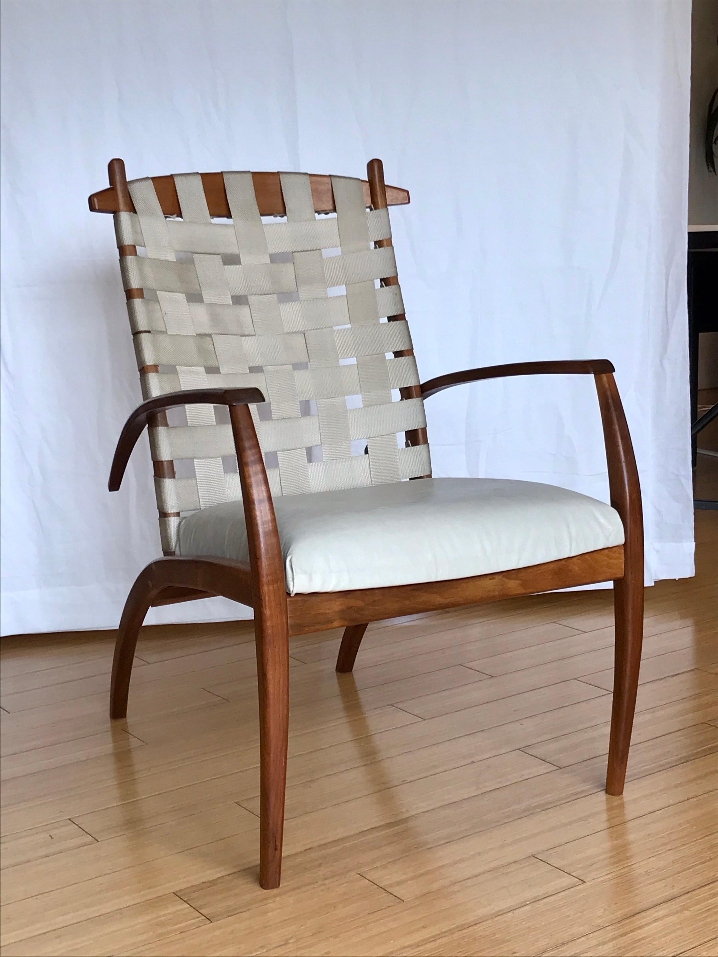 A unique design
hand crafted, appears to be walnut or other with nice bent wood detailing
parachute strap backrest with light grey leather seat
sturdy, comfy and stout 
statement / accent piece.