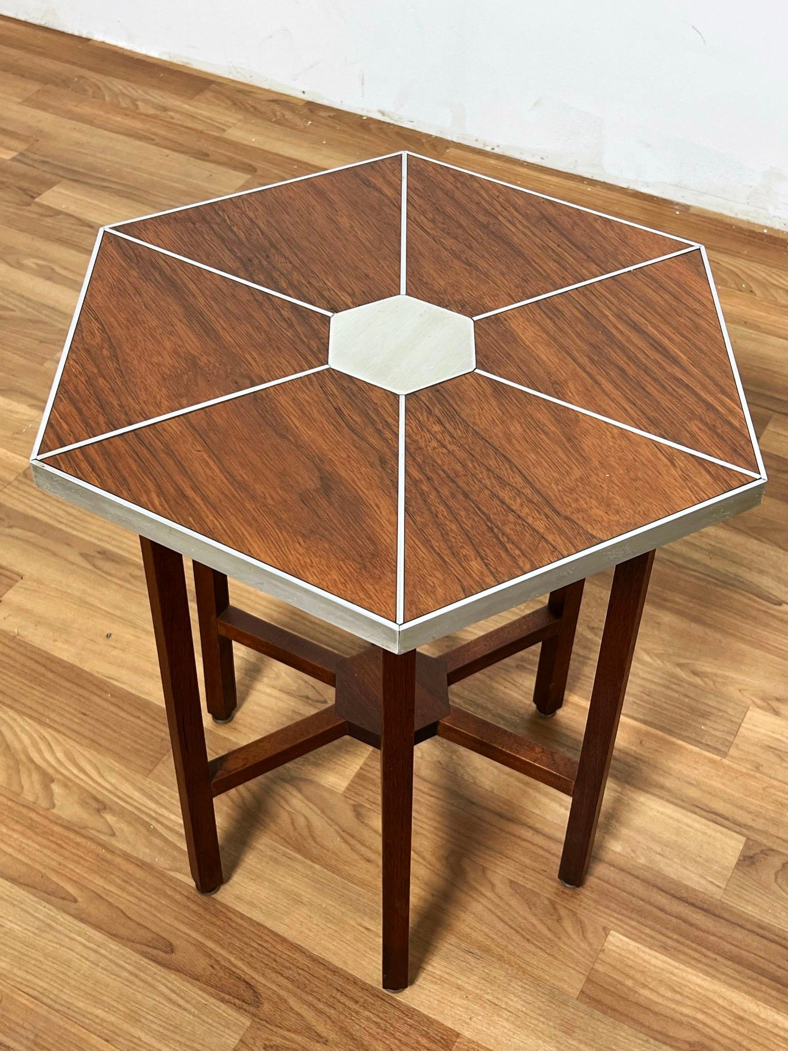 A hexagonal side table in teak with aluminum inlay, which was exhibited in the Spanish Pavilion during the 1964 New York Worlds Fair. Its jet age design echoes some of the early 60s work of designers such as Paul Evans and Philip Powell. Part of a