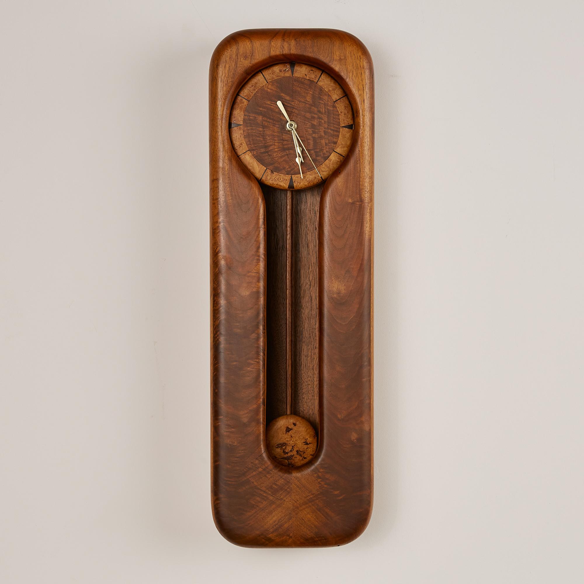 This Pendulum clock features a solid walnut frame with a stunning cathedraling that is inherent of the natural movement in the wood grain. The face of the clock appears to be floating and showcases a solid walnut center while the outer edge has a