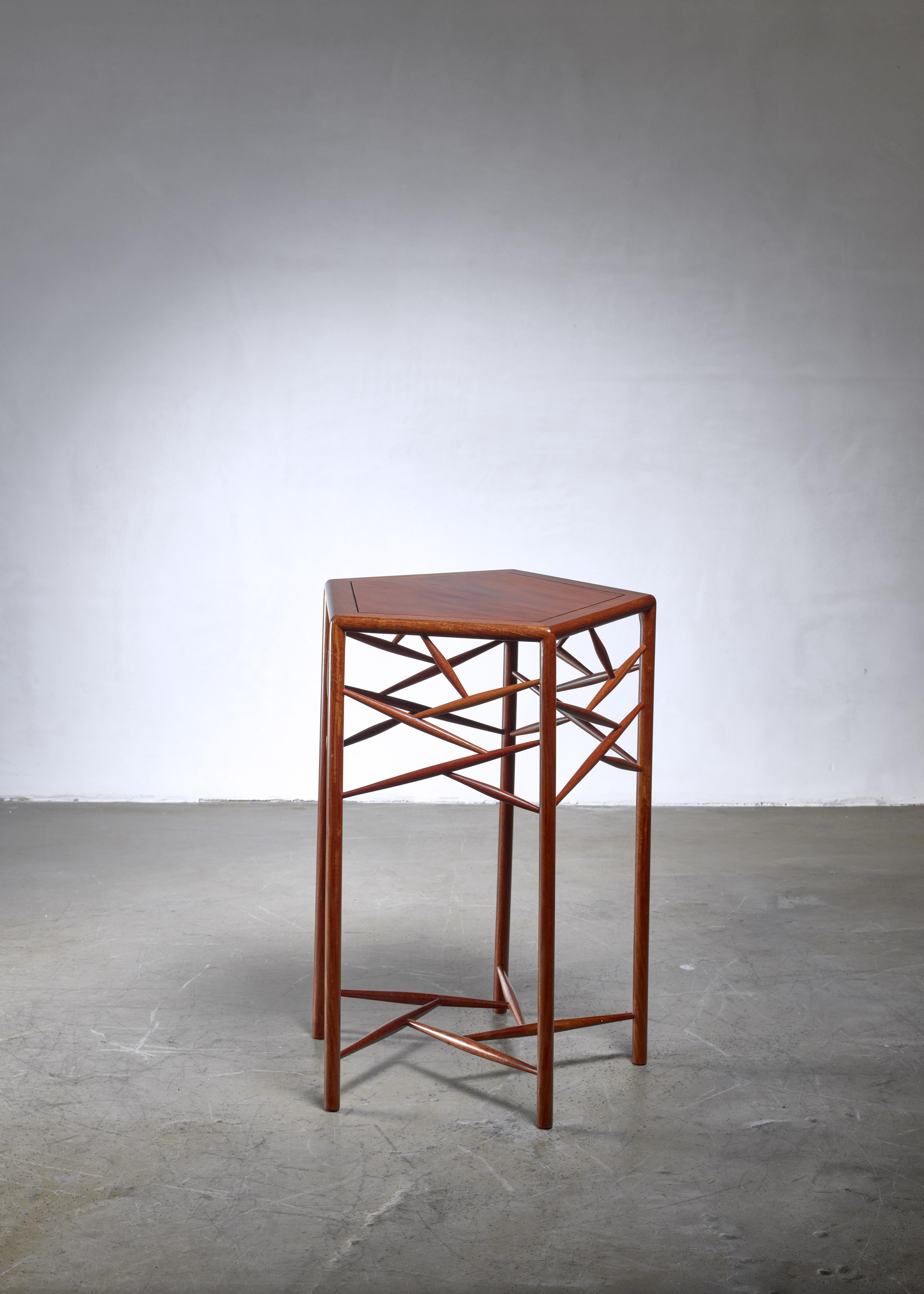 A studio craft side or guéridon table made of wood, with a pentagonal top. The tall and slim legs are stabilized by the spindles at the bottom as well as between the legs, emphasizing the pentagonal shape and giving dynamic to the table.